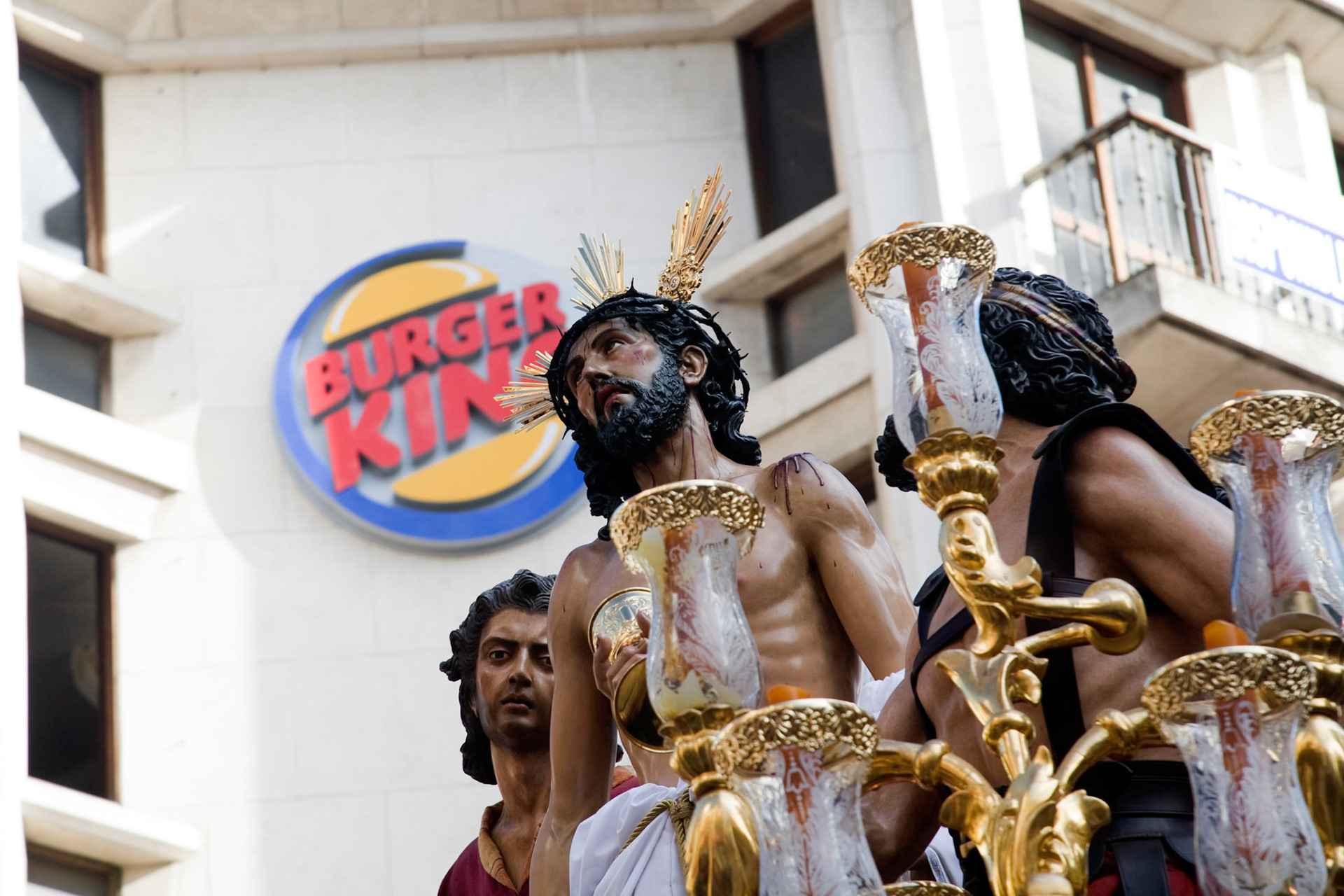 An image of Christ in front of Burger King logo during Holy Week processions, Seville, Spain
