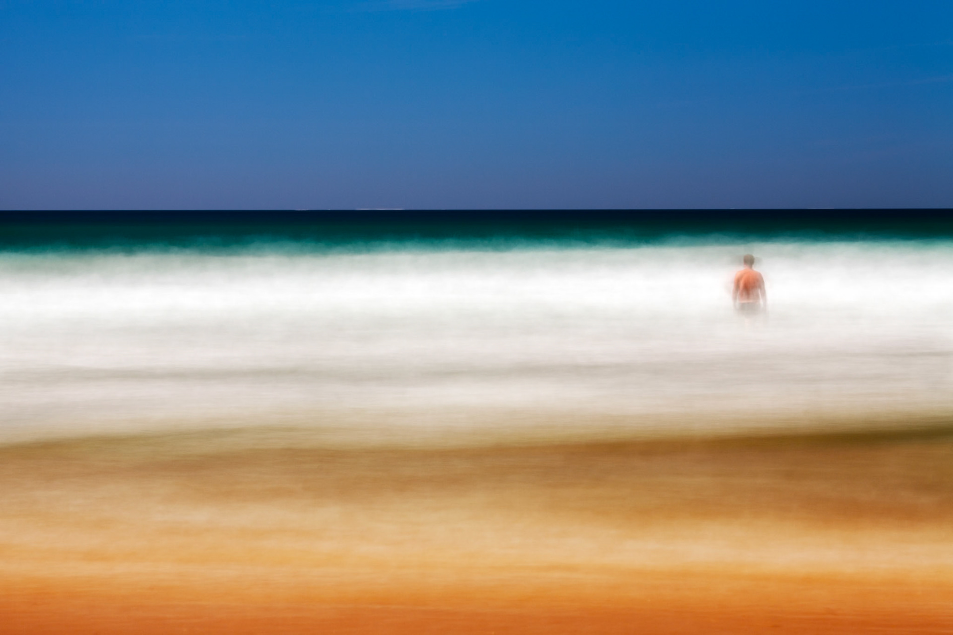 Man on a beach staring at the sea. Daylight long exposure shot by the use of neutral density filters. Model release available.