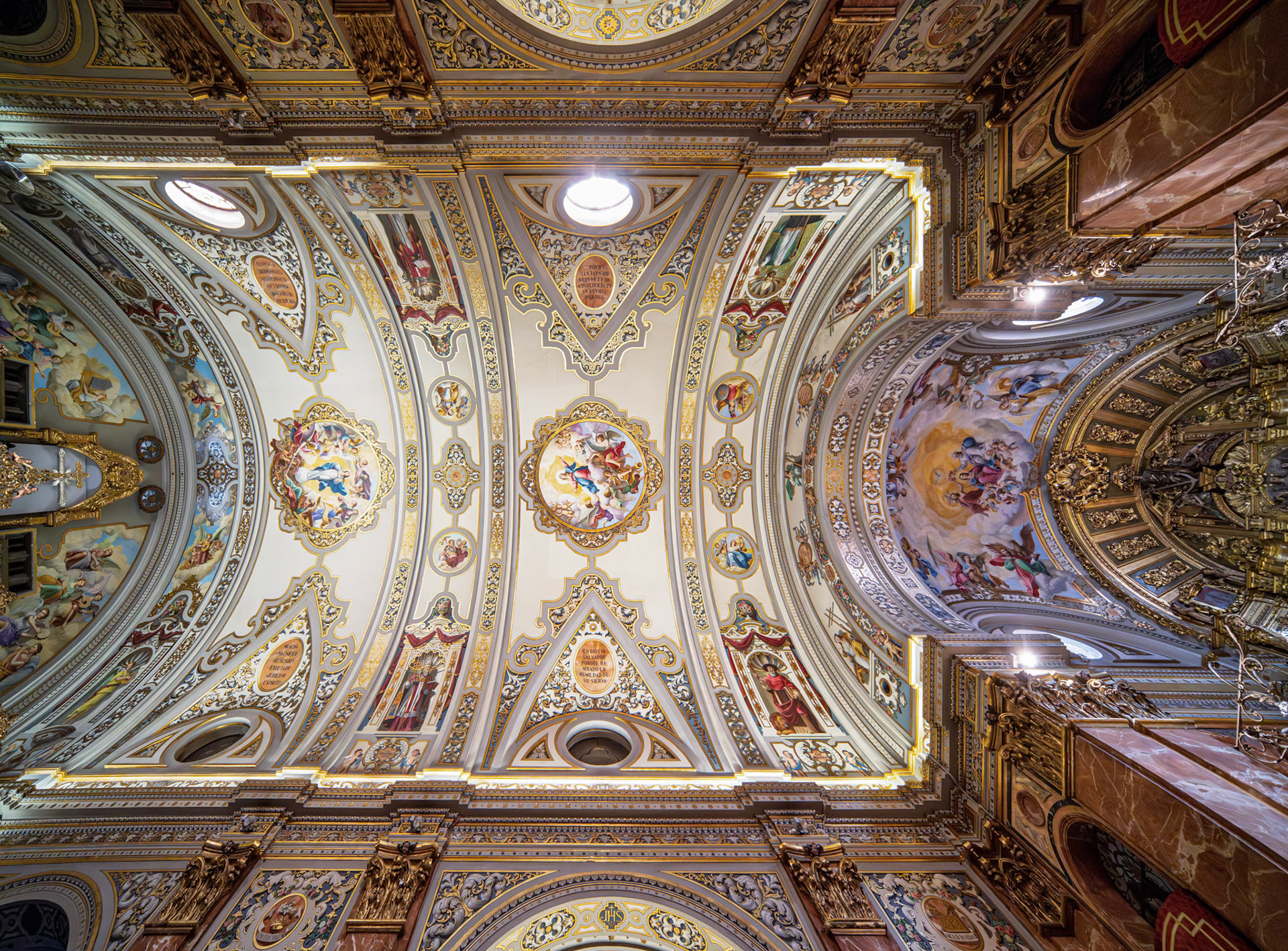 Gilded frames and colorful frescoes adorn the ceiling of Basílica de la Macarena, highlighting neobaroque design and deep devotion in Seville.