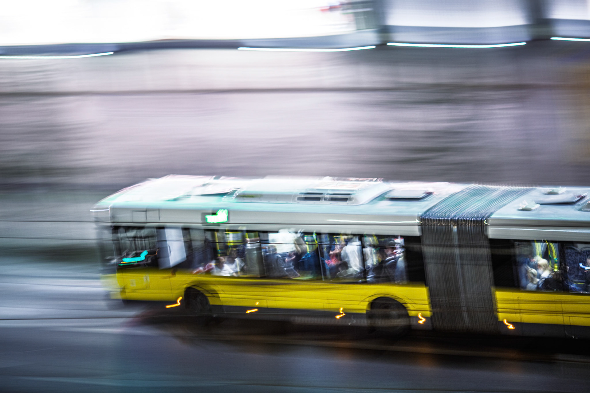 A bus glides through Berlin at night, illuminated by city lights and the glow of its own headlights. The motion captures the vibrant urban life.