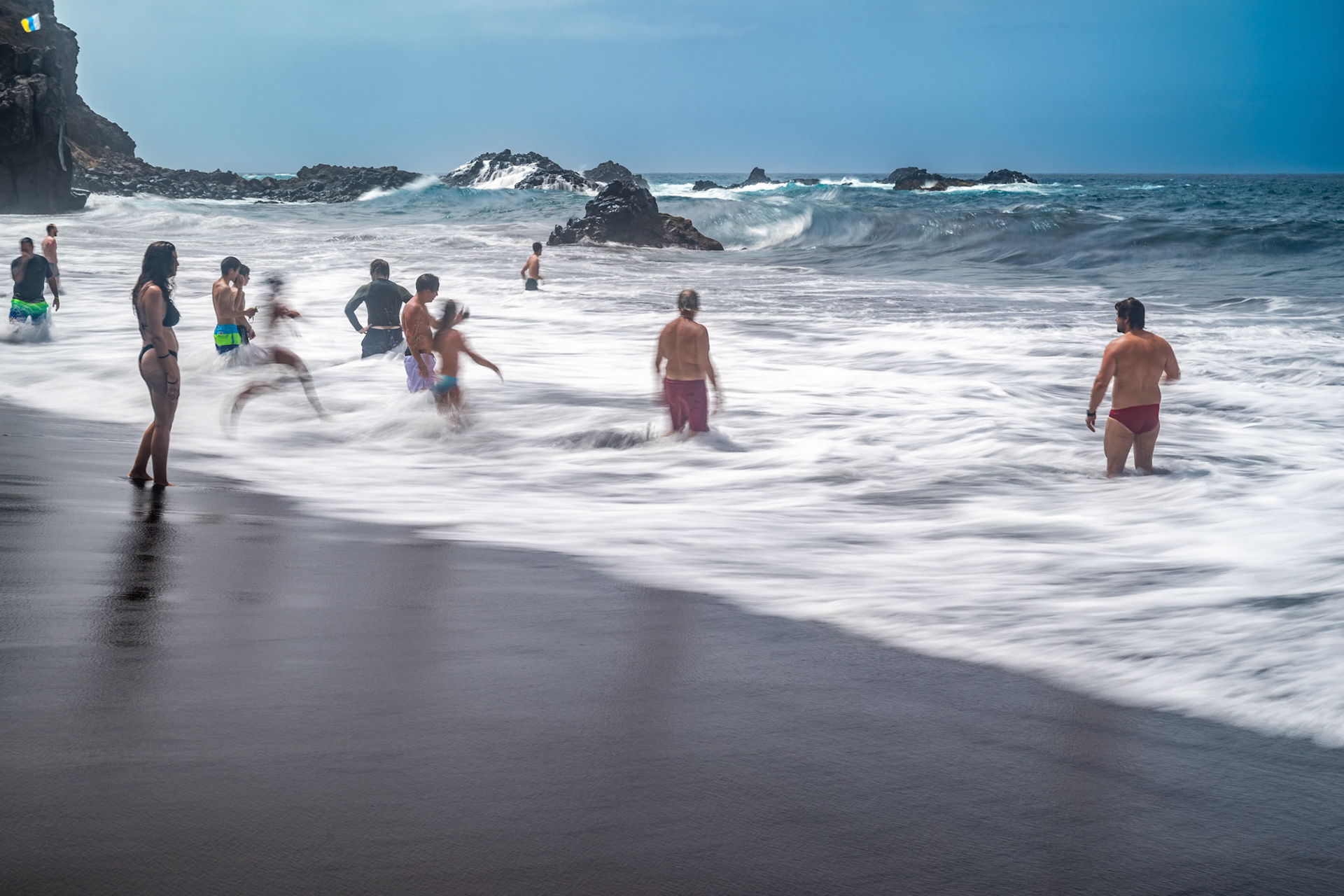 Bathers enjoying the waves at Bollullo Beach on the north coast of Tenerife in La Orotava, Canary Islands, Spain. Long exposure shot.