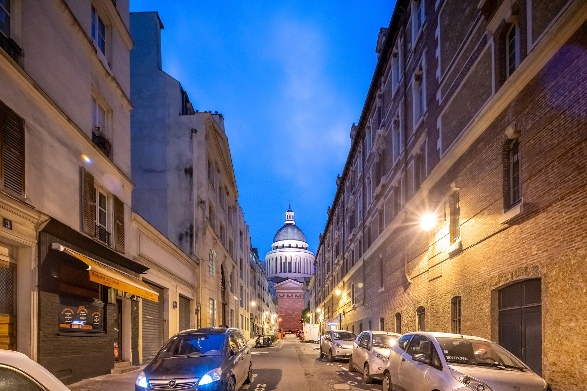 Dusk settles over Rue Valette with Le Panthéons dome illuminated in the background in Paris.