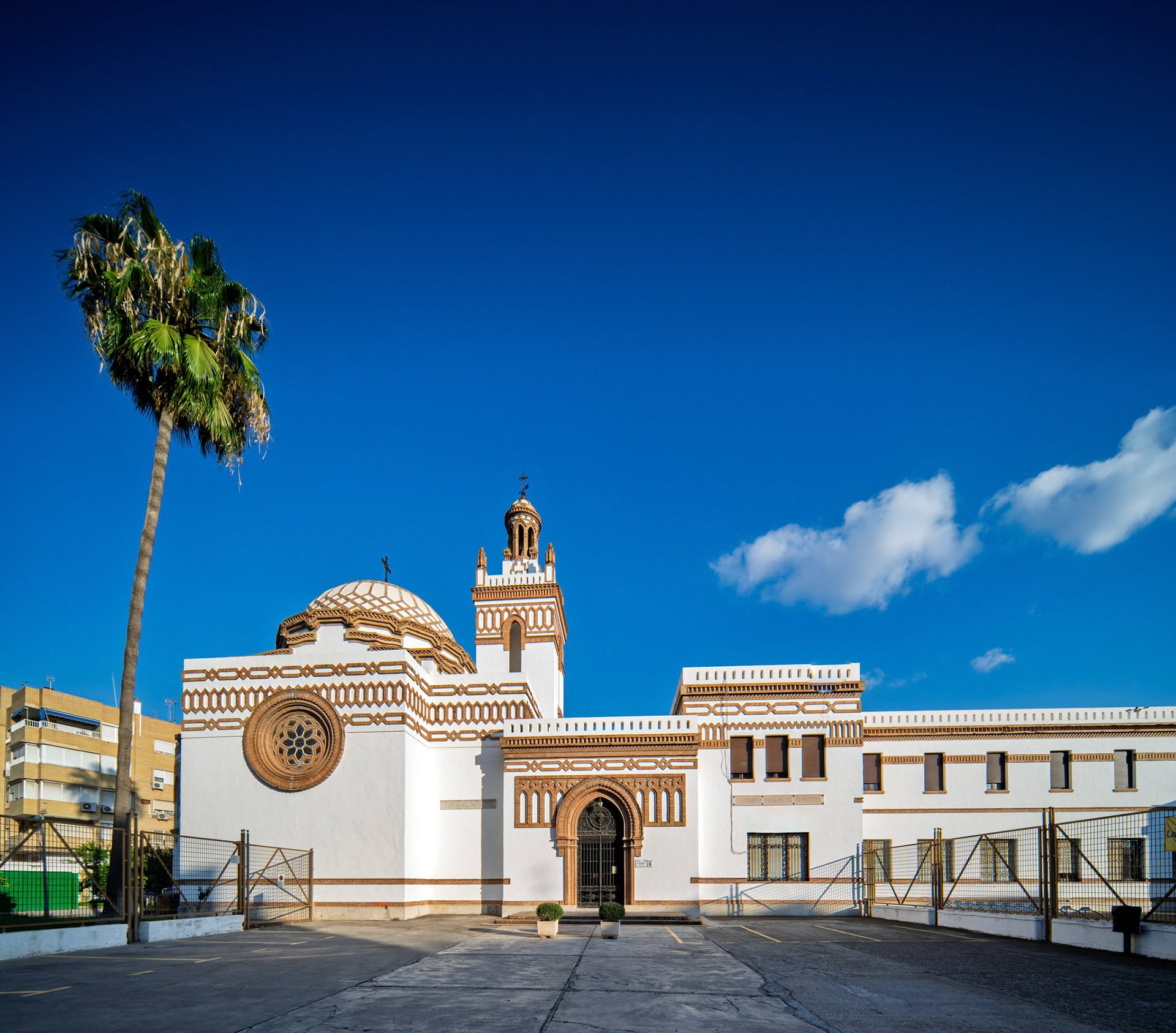 Captures the La Salle Felipe Benito School, showcasing its Neomudejar architecture designed by Antonio Yllanes del Rio. Seville, Spain, sunny day.