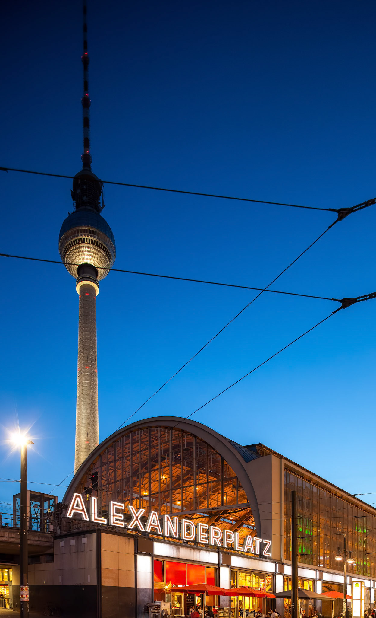 The stunning architecture of Alexanderplatz showcases the Fernsehturm as evening descends over Berlin\'s vibrant Mitte district.