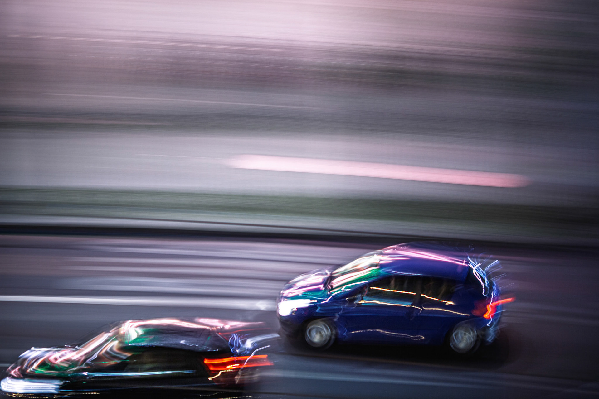Cars speed by in a vibrant blur at night in Berlin, capturing the city's lively atmosphere and urban energy with colorful lights.