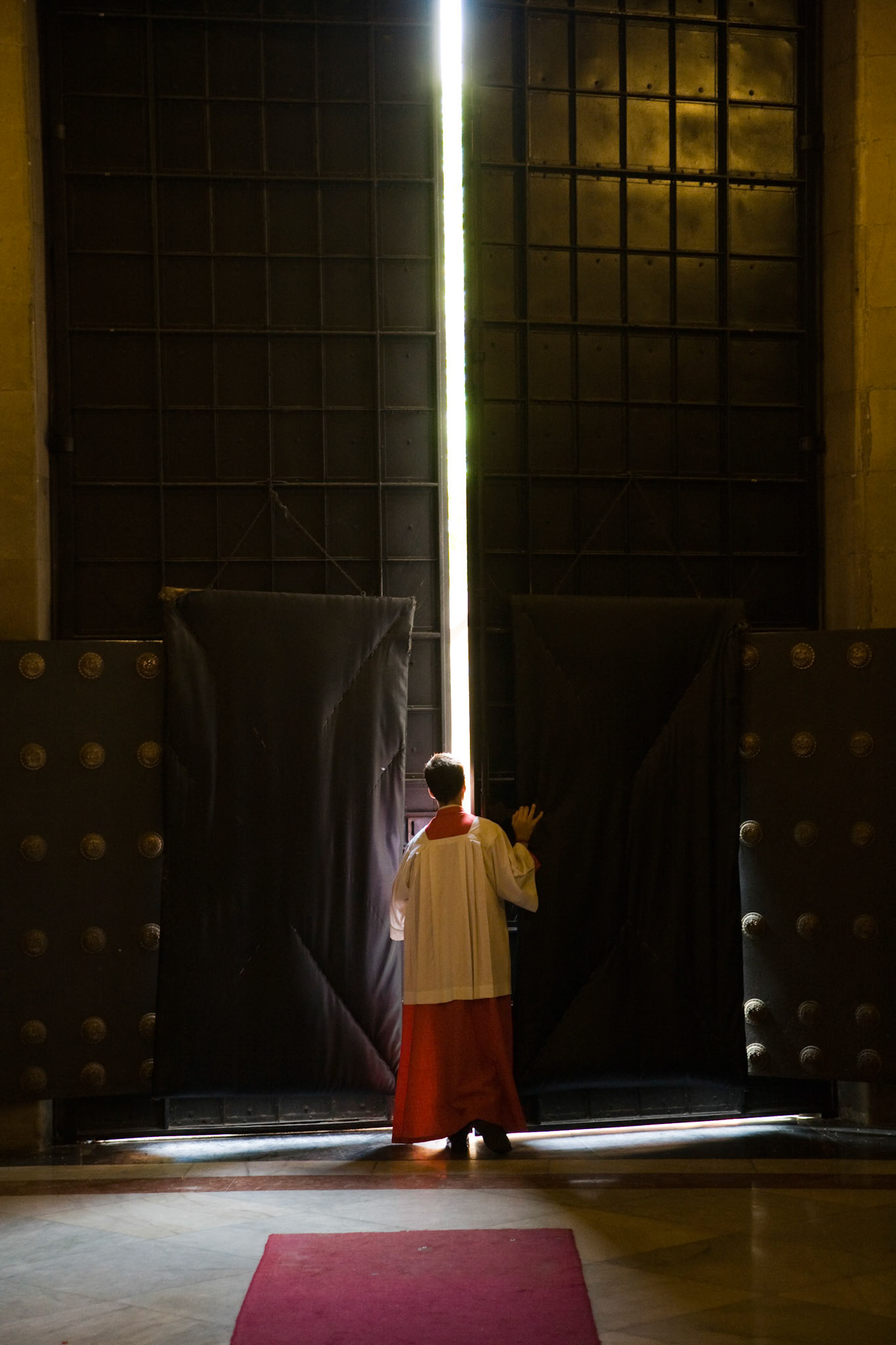 Altar boy closing a church door, Seville, Spain