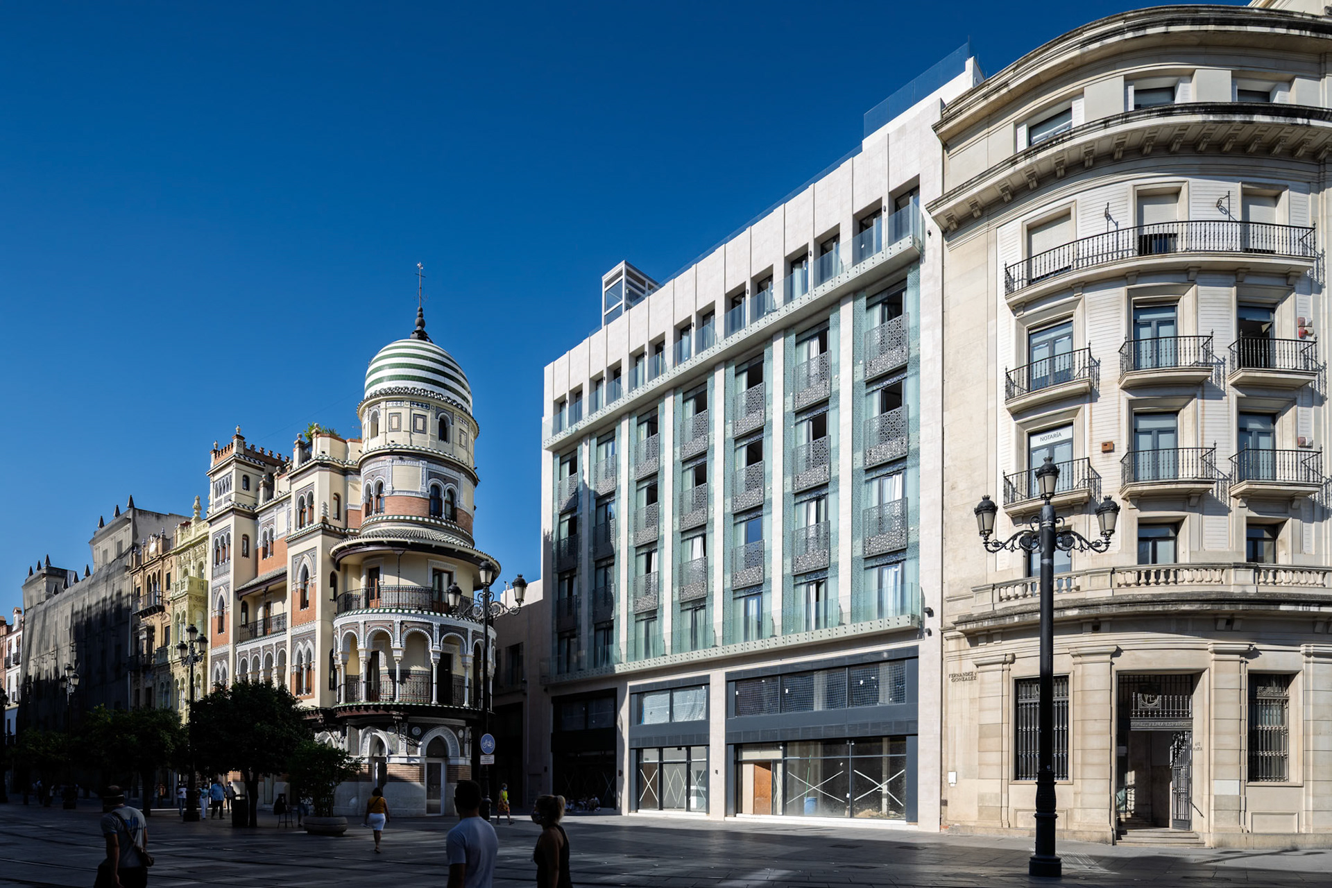 The dome of the Adriatica building dominates the Avenida, surrounded by ornate facades and lively pedestrians in sunny Seville.