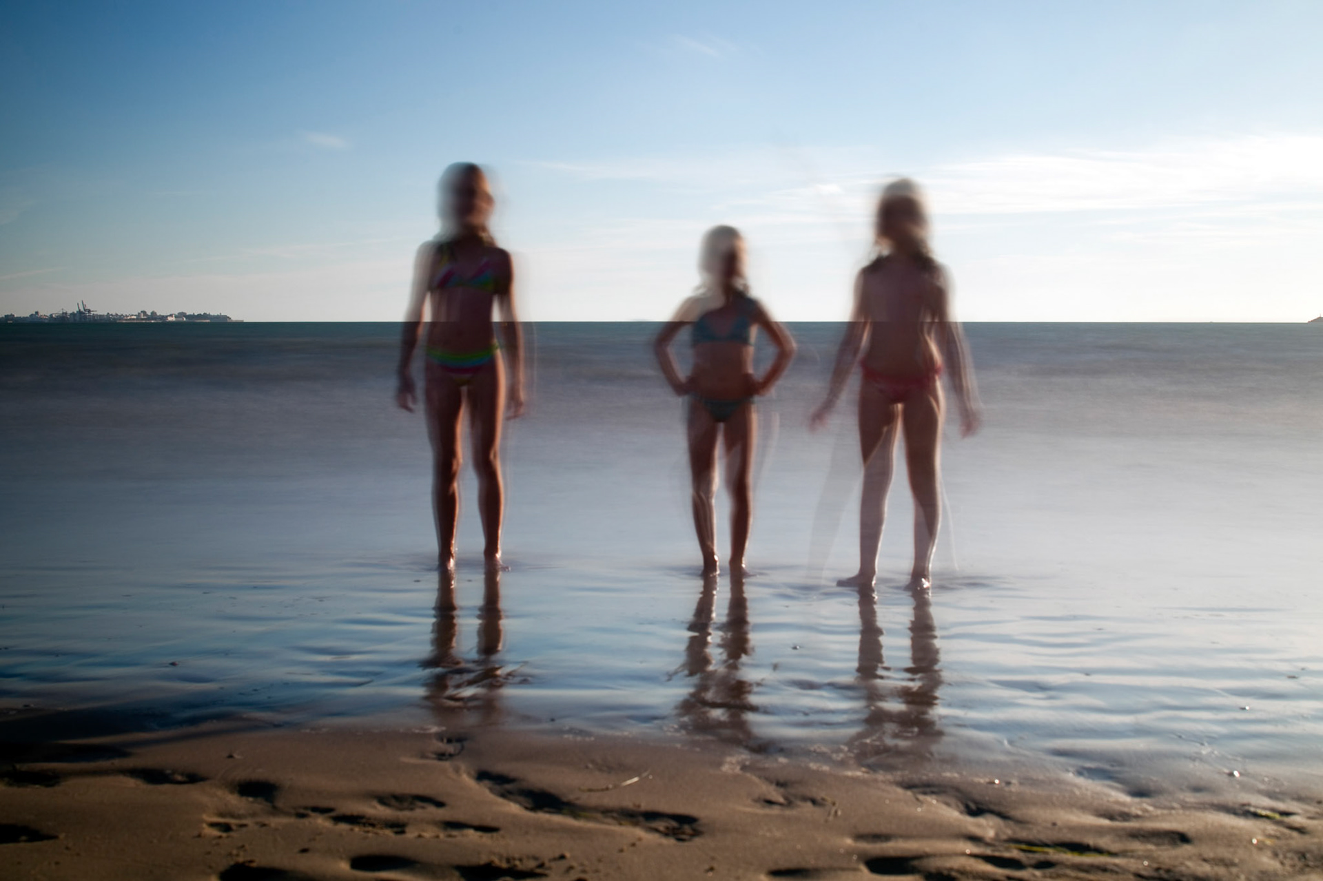 Little girls standing on the beach, El Puerto de Santa Maria, Spain. Daylight long exposure shot by the use of neutral density filters.