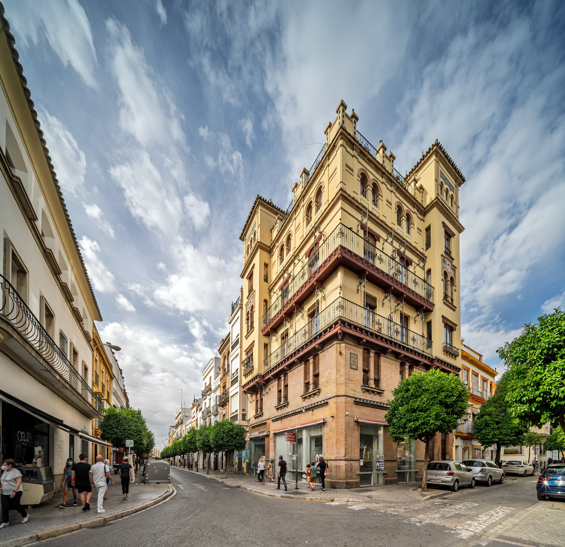 Regionalist building on Feria Street—designed by José Espiau in 1921, with ornate balconies, brickwork, and ceramic medallions blending Sevillian tradition and early 20th-century revival