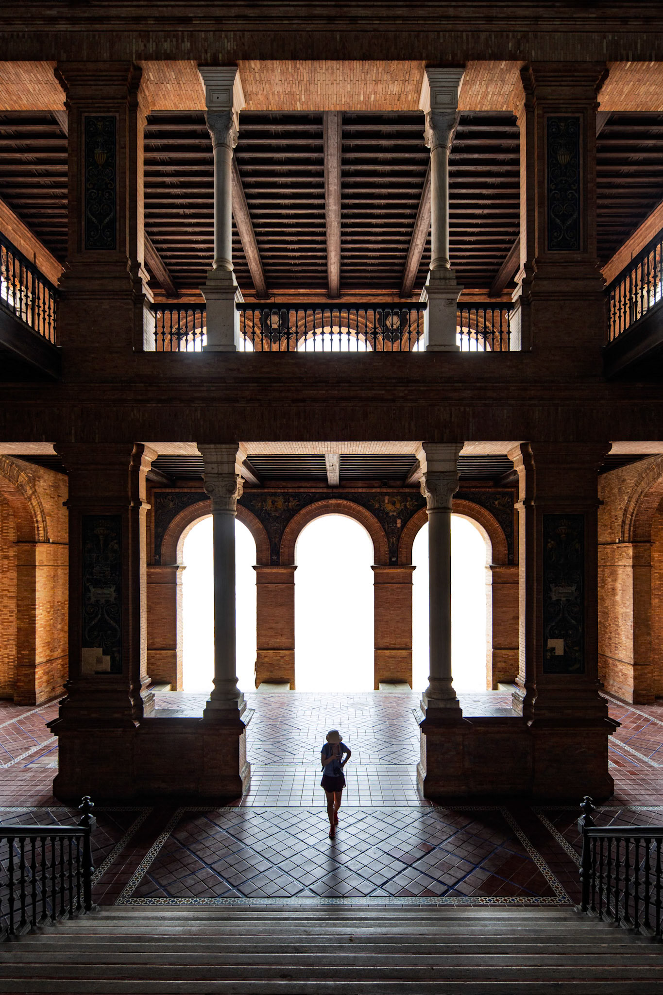 Visitors admire Plaza de Espana's stunning architecture and elegant arches, an iconic Seville landmark, under soft lighting.
