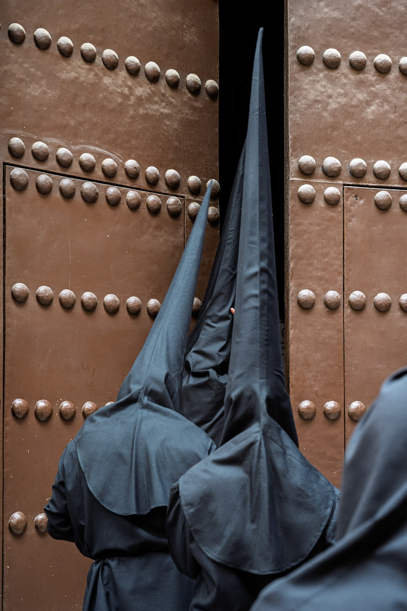 Black-clad Nazarenos of the Santa Marta Brotherhood arrive at San Andrés Church in Seville for their solemn Holy Monday procession during Holy Week.