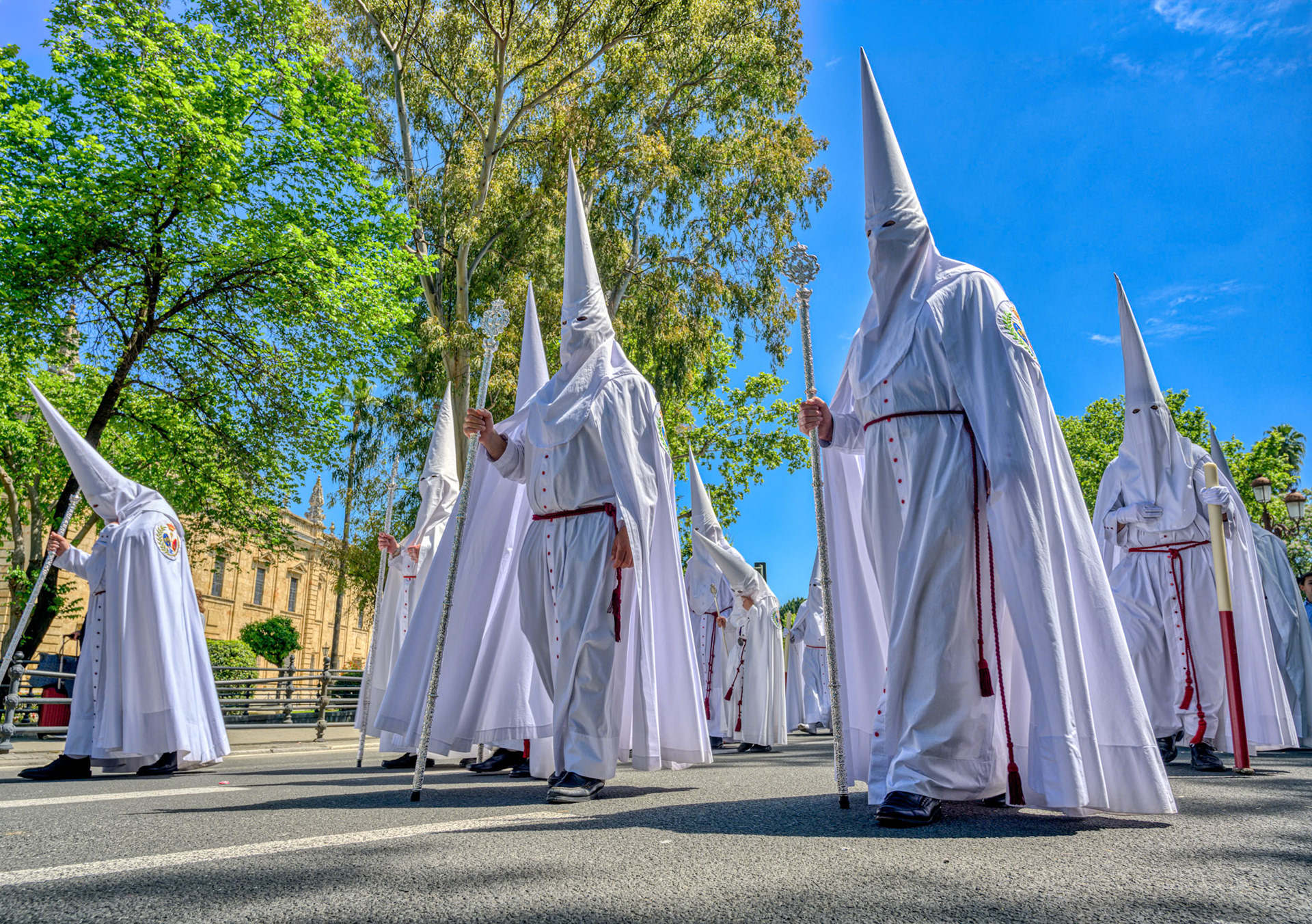 White Nazarenos of the Brotherhood of La Paz participate in the Palm Sunday procession during Holy Week in Seville, Andalusia, Spain.