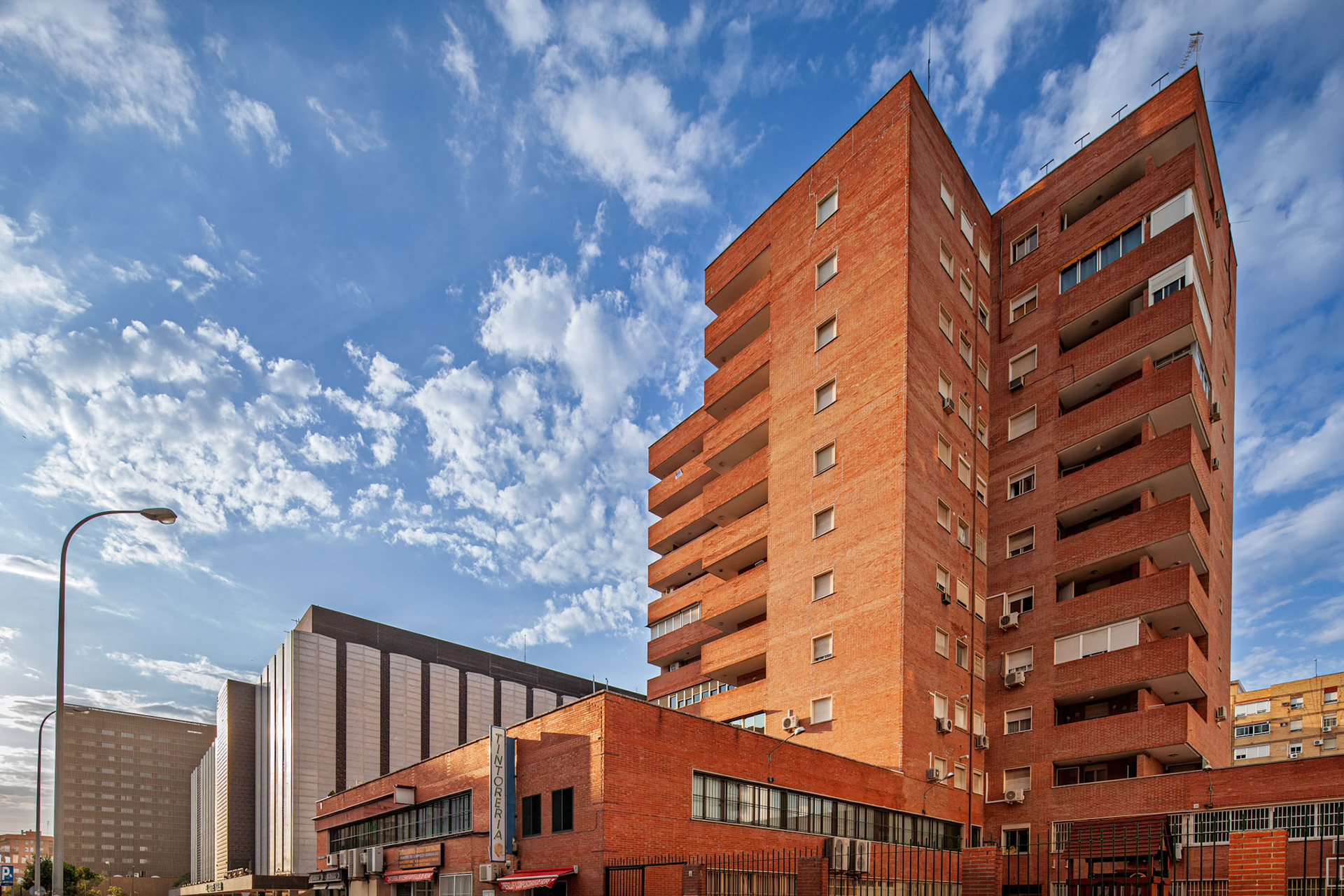 Discover Seville's Nervion district. This image showcases brick apartment buildings under a bright blue sky, reflecting the city's architectural style.