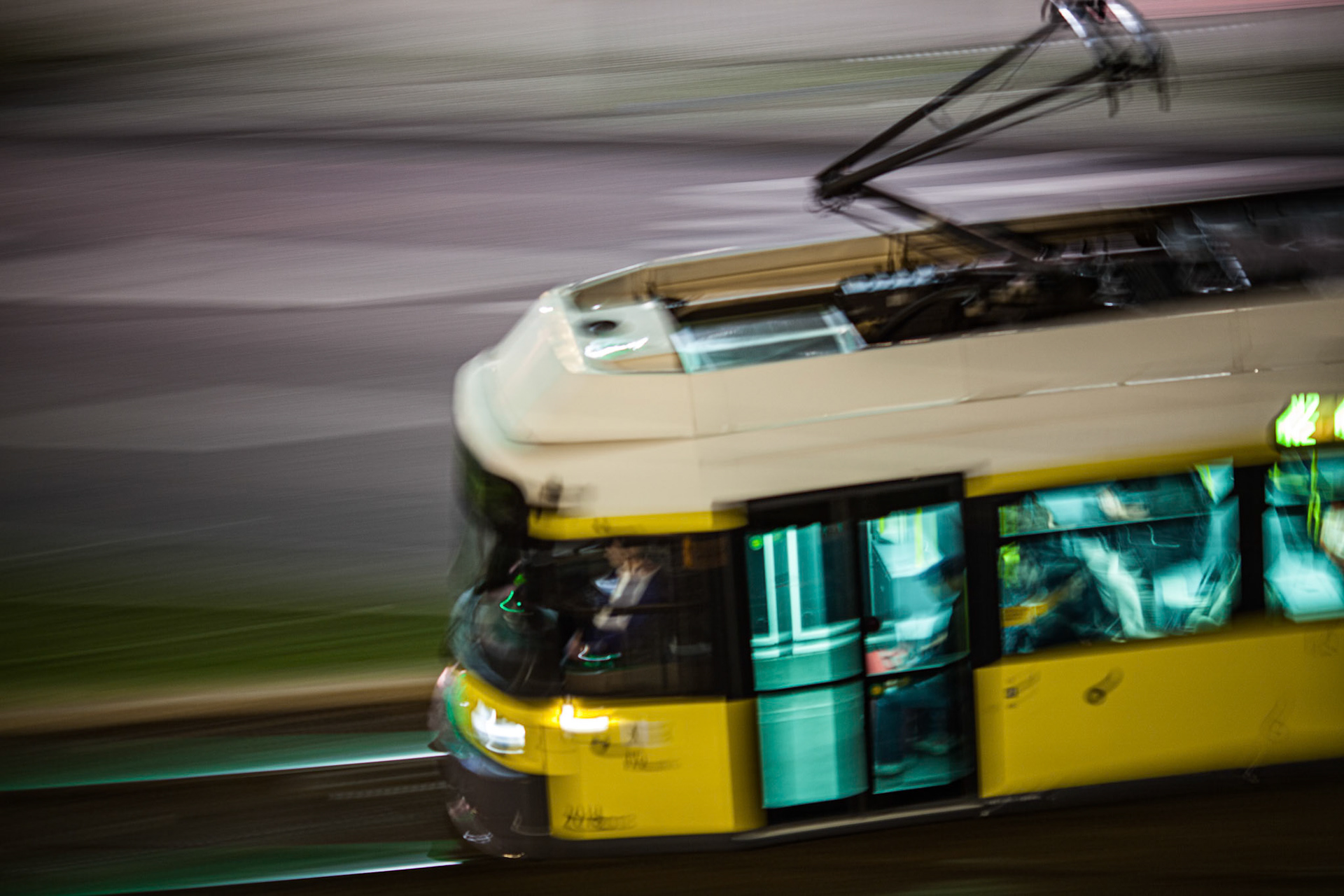 A tram moves swiftly through the streets of Berlin at night, its lights shining brightly in the urban landscape while the city sleeps.