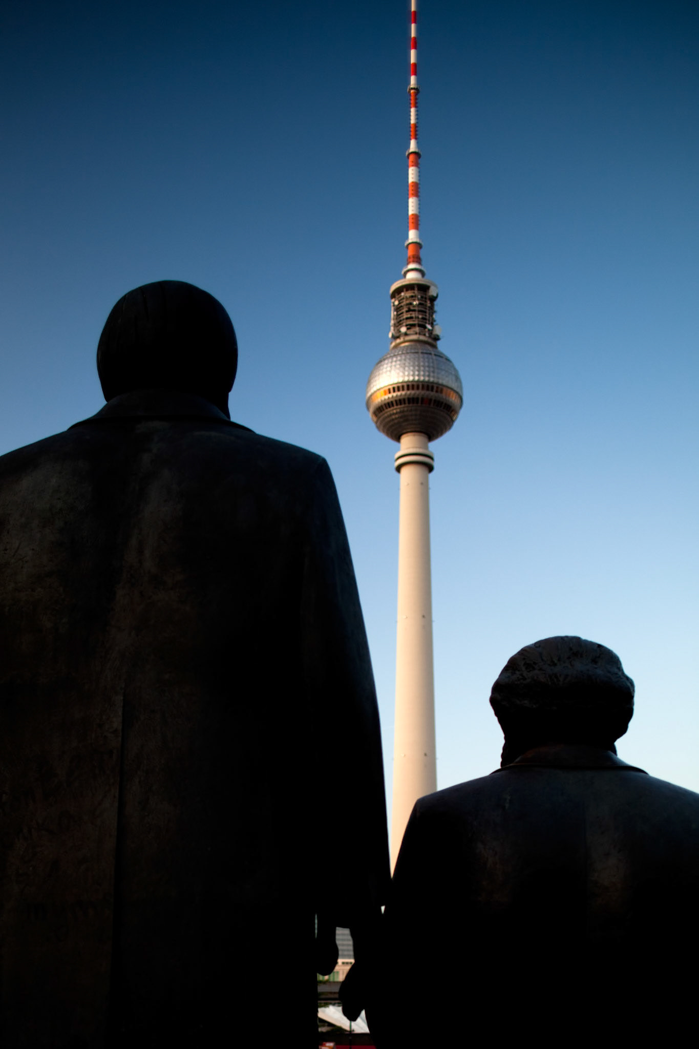 The statues of Karl Marx and Friedrich Engels stand prominently against the Berlin skyline, overlooking the Fernsehturm.