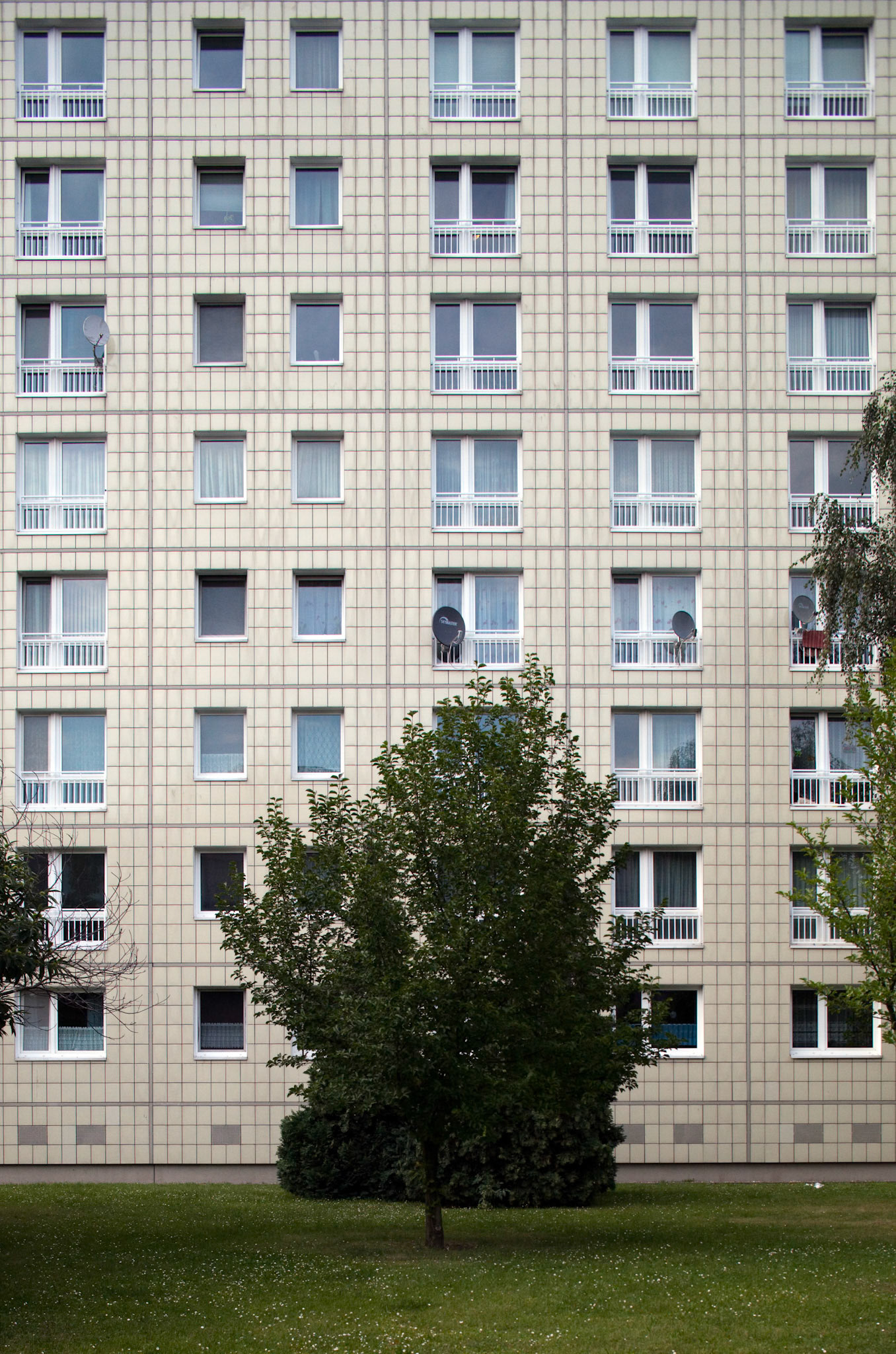 The residential building on Alexander Street features distinct architecture, surrounded by green space in former East Berlin, Germany.