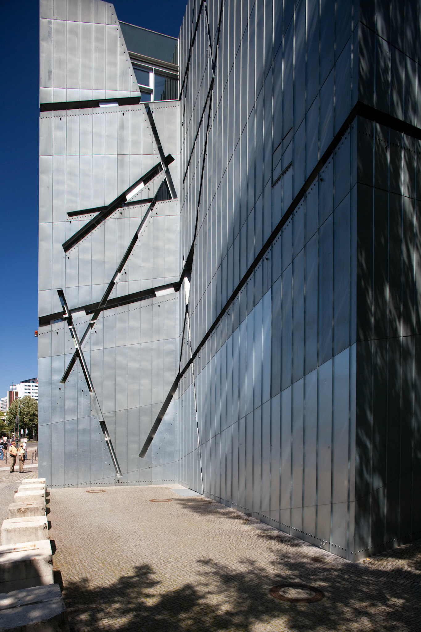 The striking exterior of the Jewish Museum Berlin features contemporary design by Daniel Libeskind, set against a clear blue sky.
