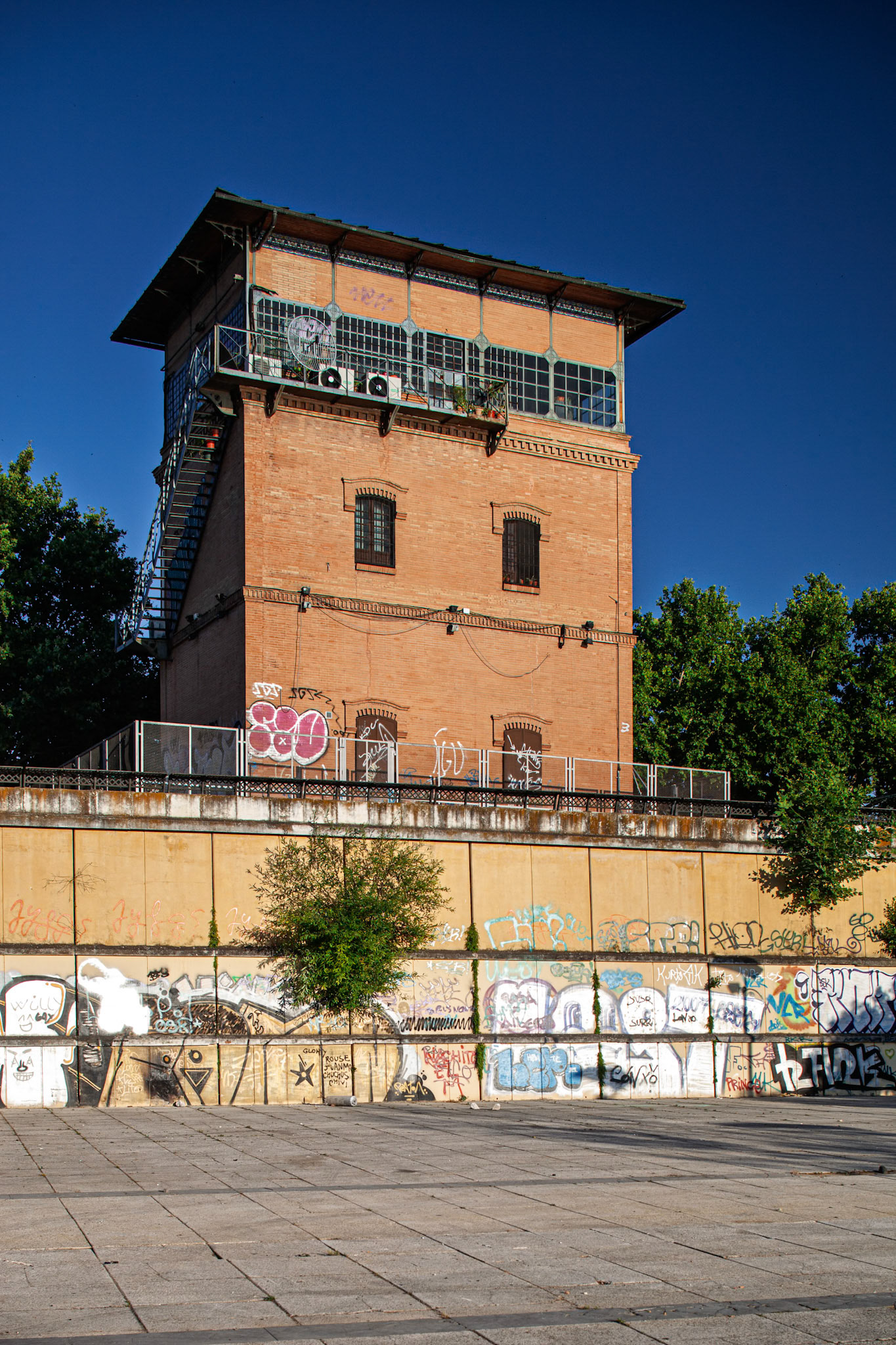 Discover former railroad tower in Seville, Spain. Explore its brick architecture, graffiti art and unique charm in this vibrant urban landscape.