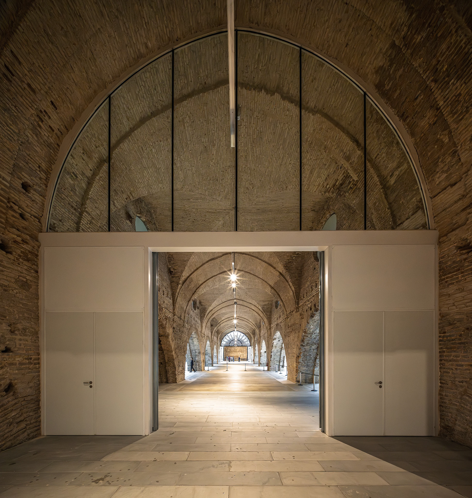 Atarazanas in Seville showcases stunning vaulted brick arches and restored medieval shipyard architecture behind a modern partition.