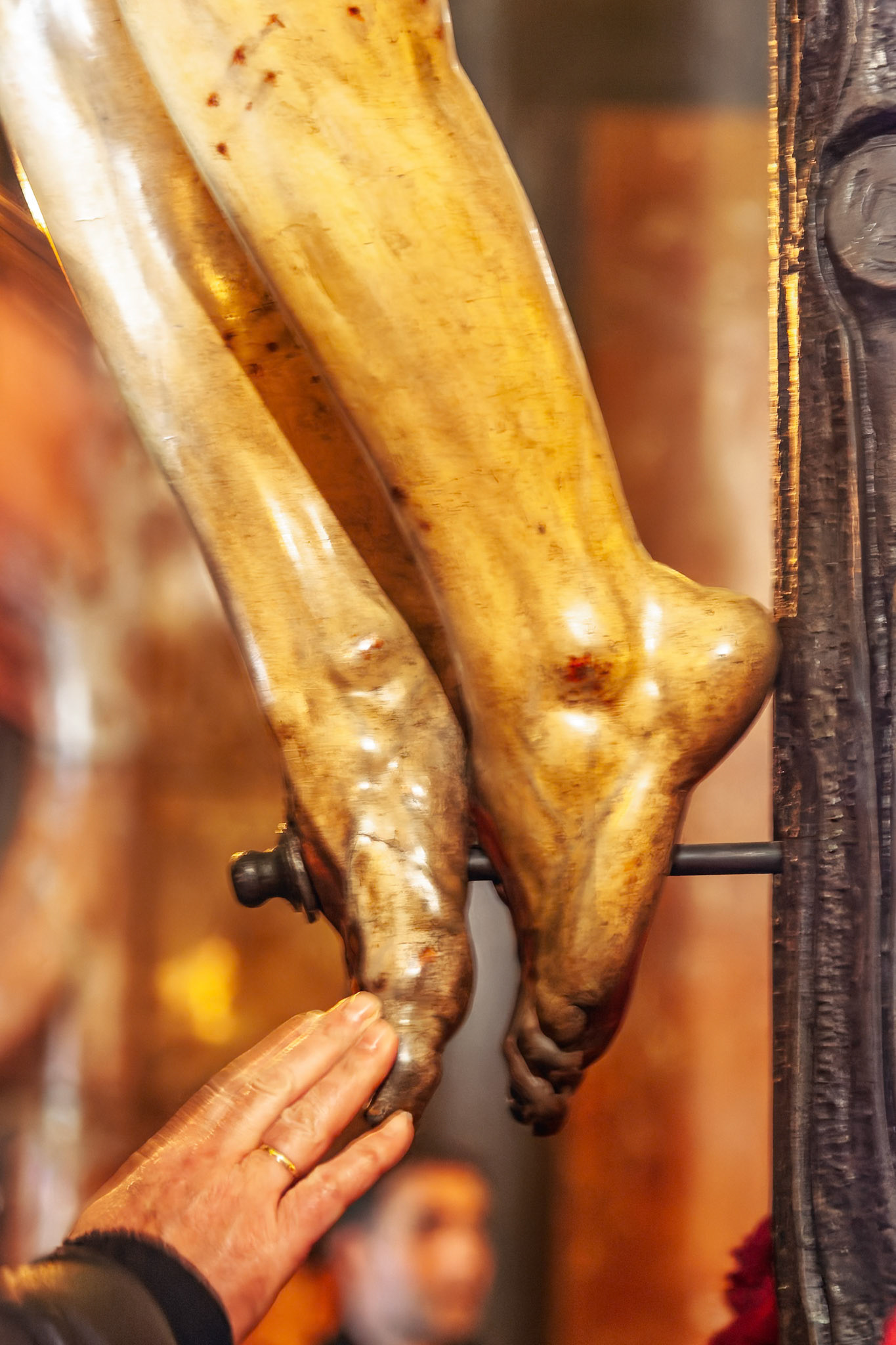 A hand gently caresses the feet of Cristo del Calvario inside Magdalena Church in Seville, Spain during a moment of devotion.