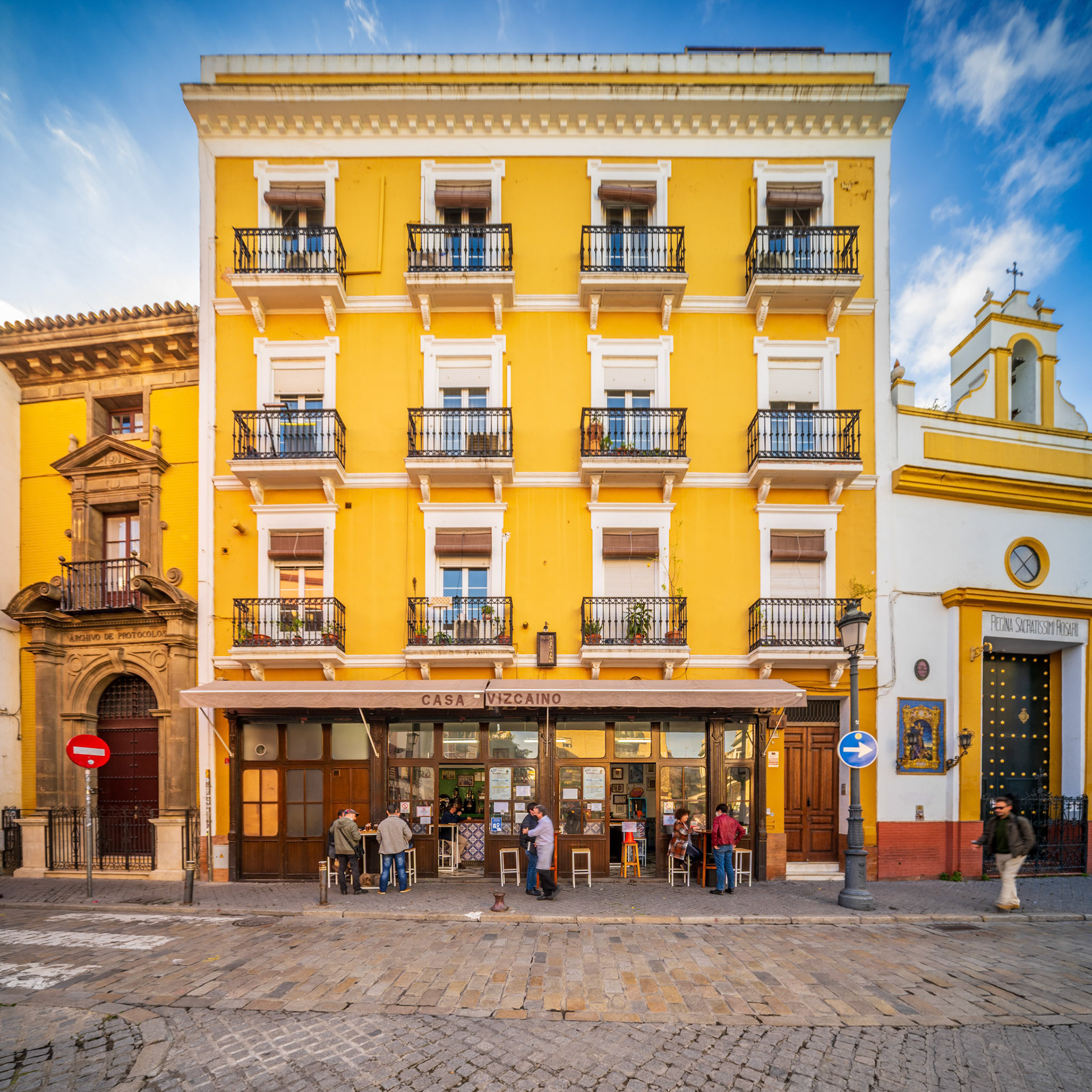 Seville, Spain, Jan 28 2021, A picturesque street scene featuring the iconic Casa Vizcaino and Montesion Chapel in Seville, Spain, showcasing vibrant architecture and local culture. People gather outside, adding life to the historic setting.