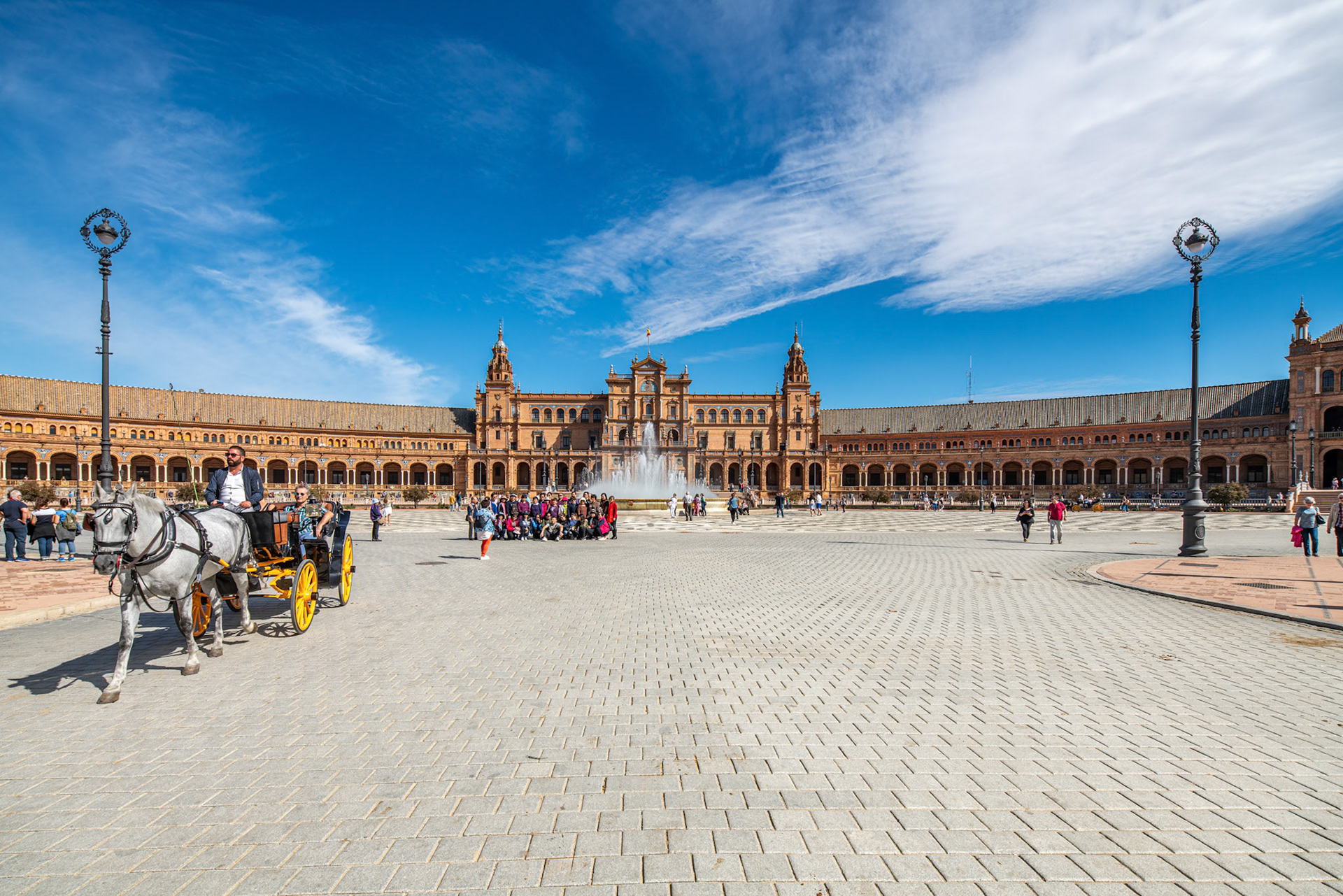 Partial view of Plaza de España center with tourists, fountain, and horse carriage.