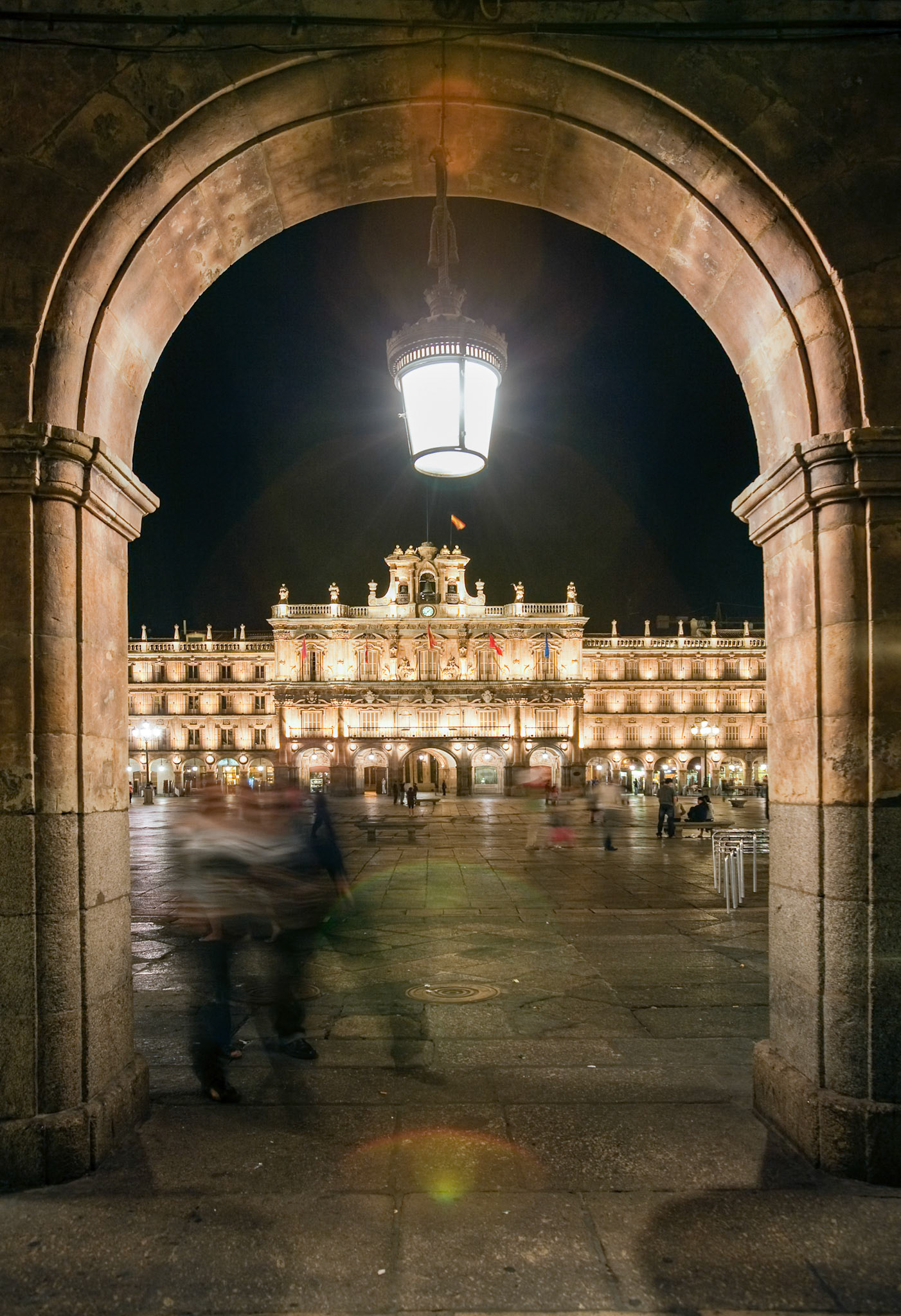 The Plaza Mayor in Salamanca beautifully illuminated at night seen through its stone portals.