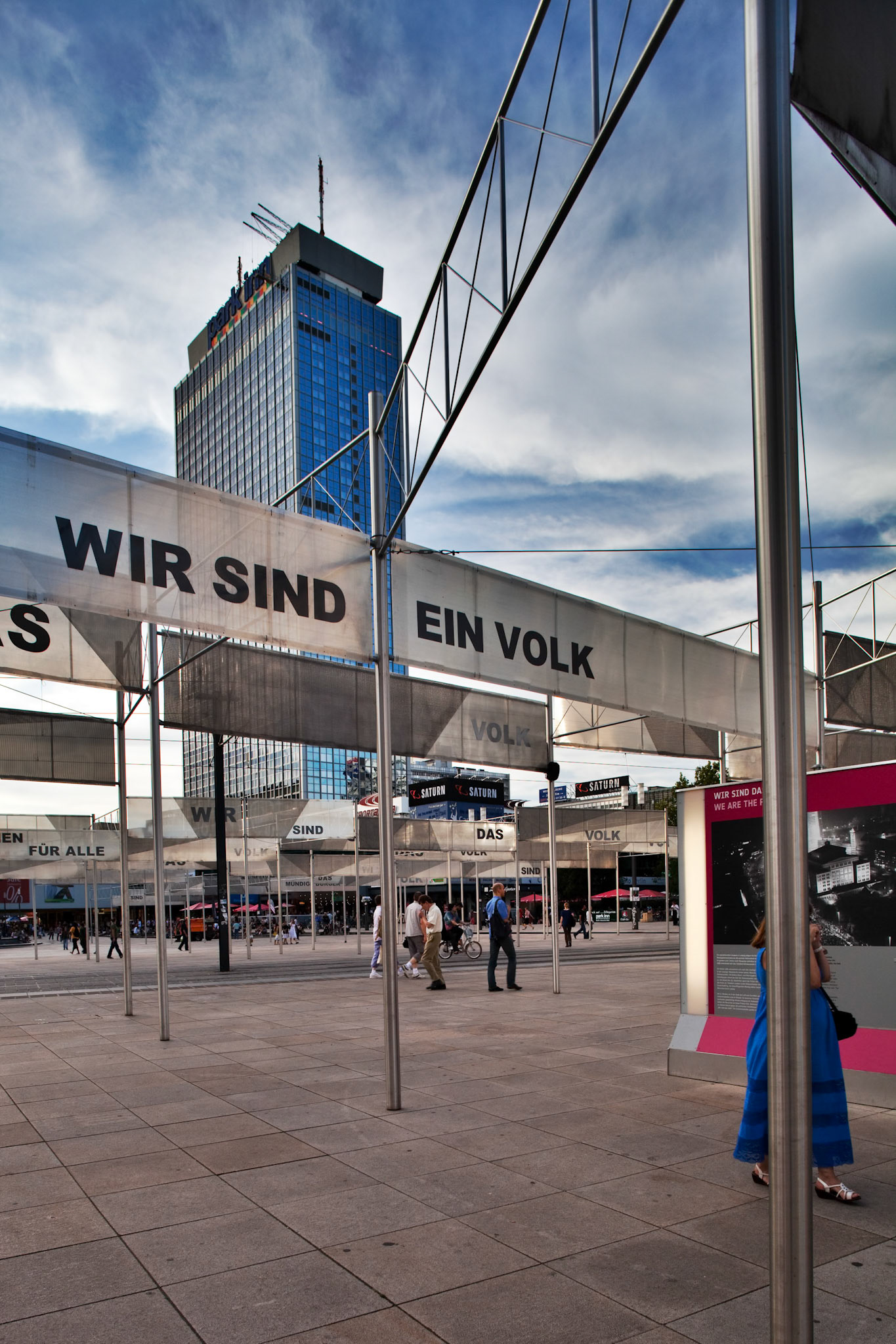 Berlin, Germany, July 21 2009, Visitors explore the Friedliche Revolution exhibit at Alexanderplatz, amidst historical landmarks and modern architecture.