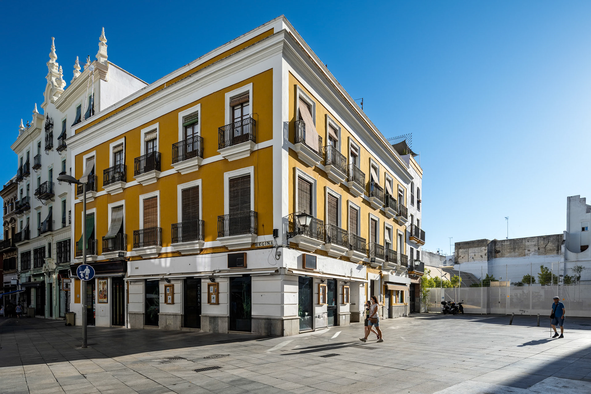 Bright sun illuminates the colorful buildings at the corner of Regina and Encarnacion in Seville, where history and daily life harmoniously coexist.
