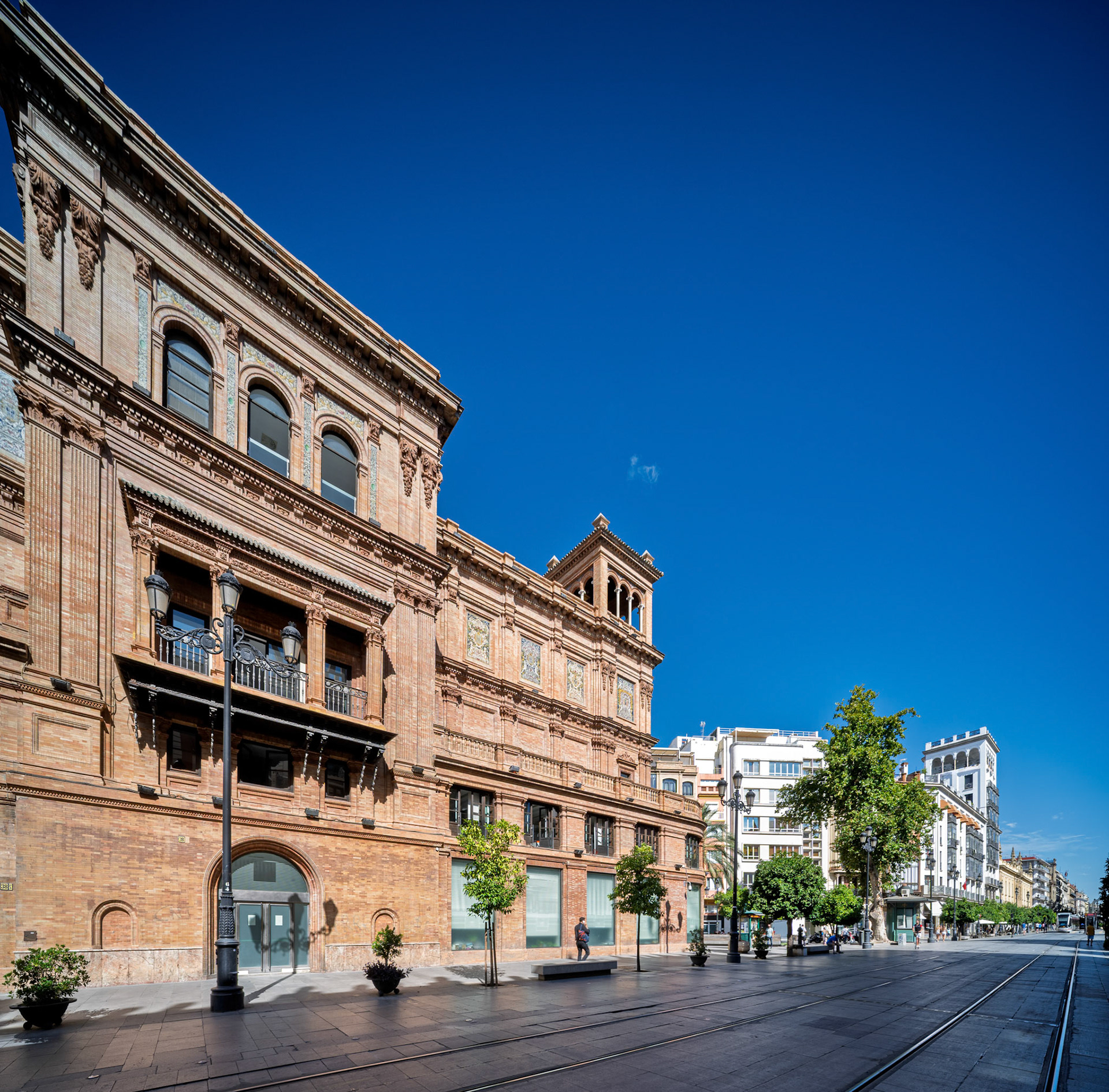 Avenida de la Constitución from the south, Seville—Coliseo building by José Espiau y Muñoz (1925–31) anchors the foreground with its ornate brickwork and tower, leading toward the Cathedral.