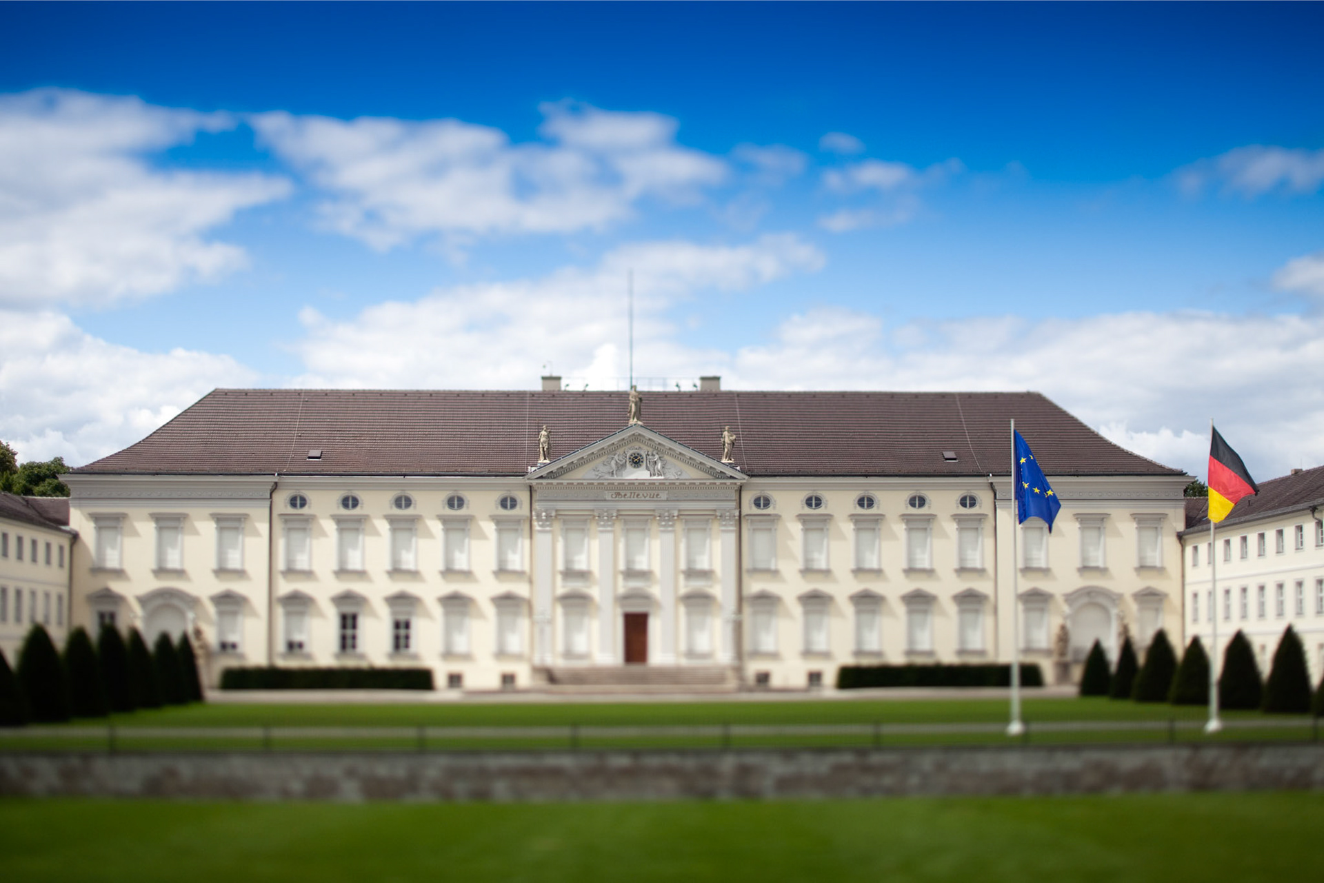 Schloss Bellevue, the German President\'s residence, stands majestically in Tiergarten, surrounded by manicured gardens under a bright sky.