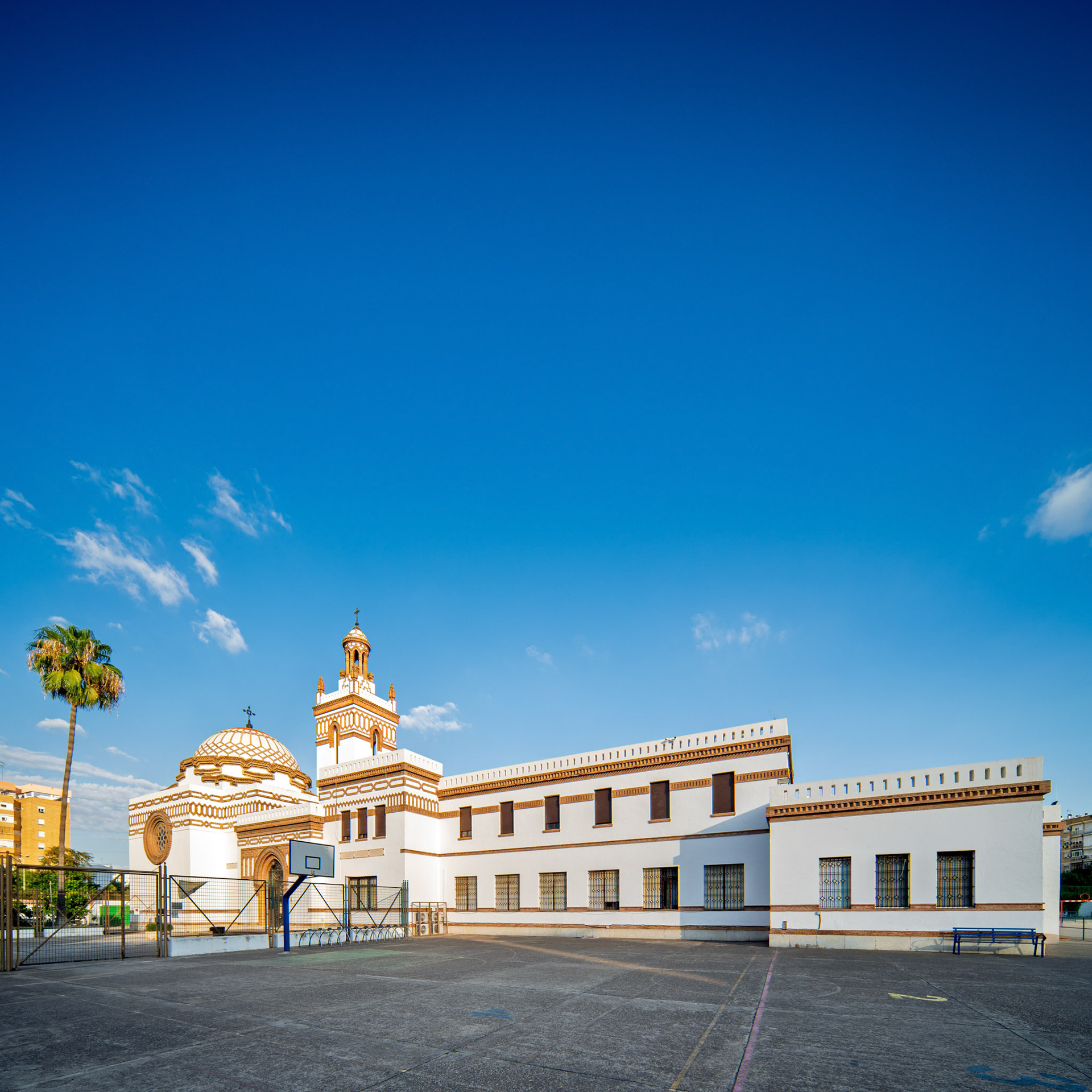 Captures the La Salle Felipe Benito School, showcasing its Neomudejar architecture designed by Antonio Yllanes del Rio. Seville, Spain, sunny day.