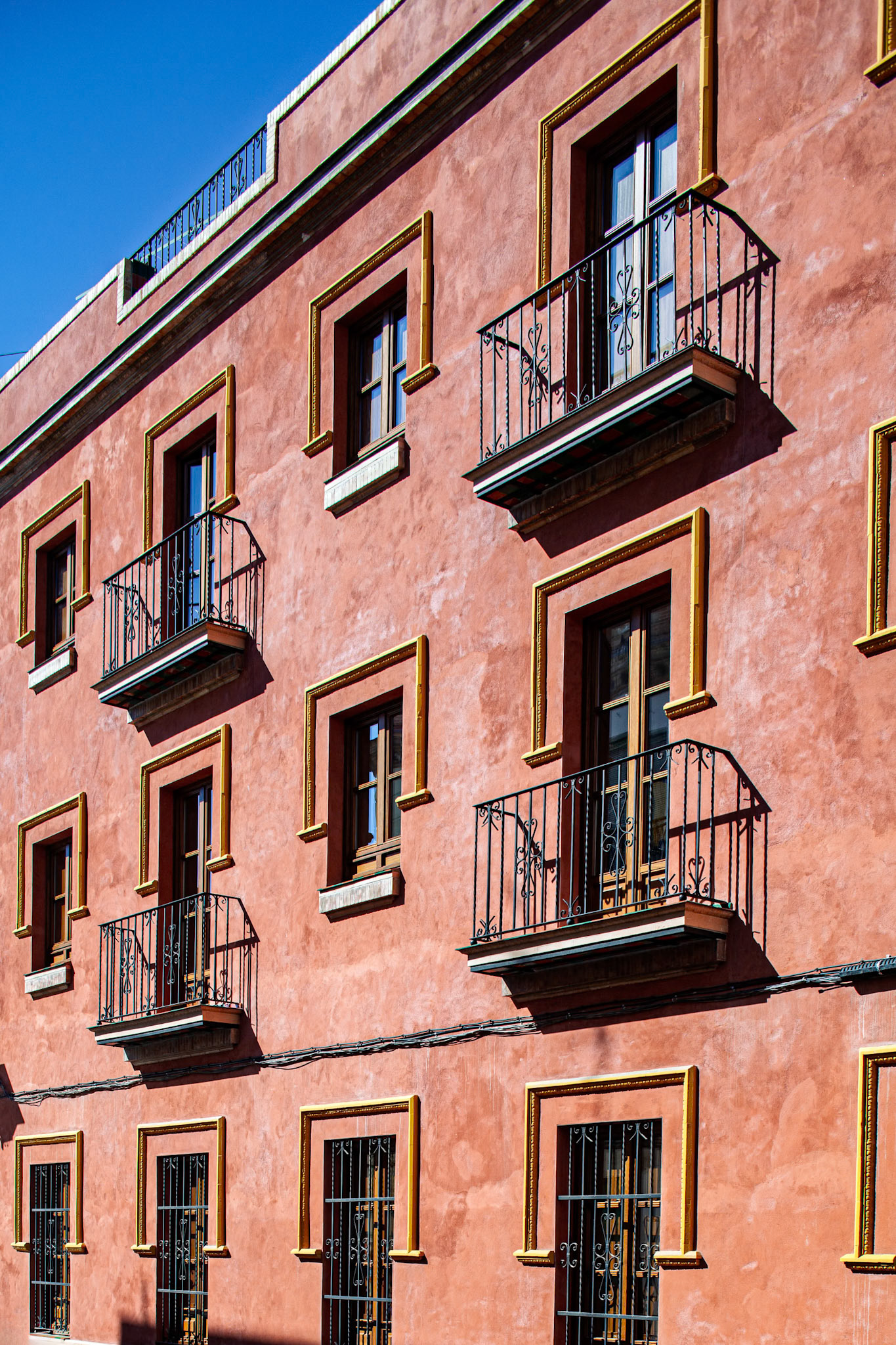 Captivating building facade with balconies graces Moravia street in Seville, Spain, showcasing unique architectural charm and Mediterranean style.
