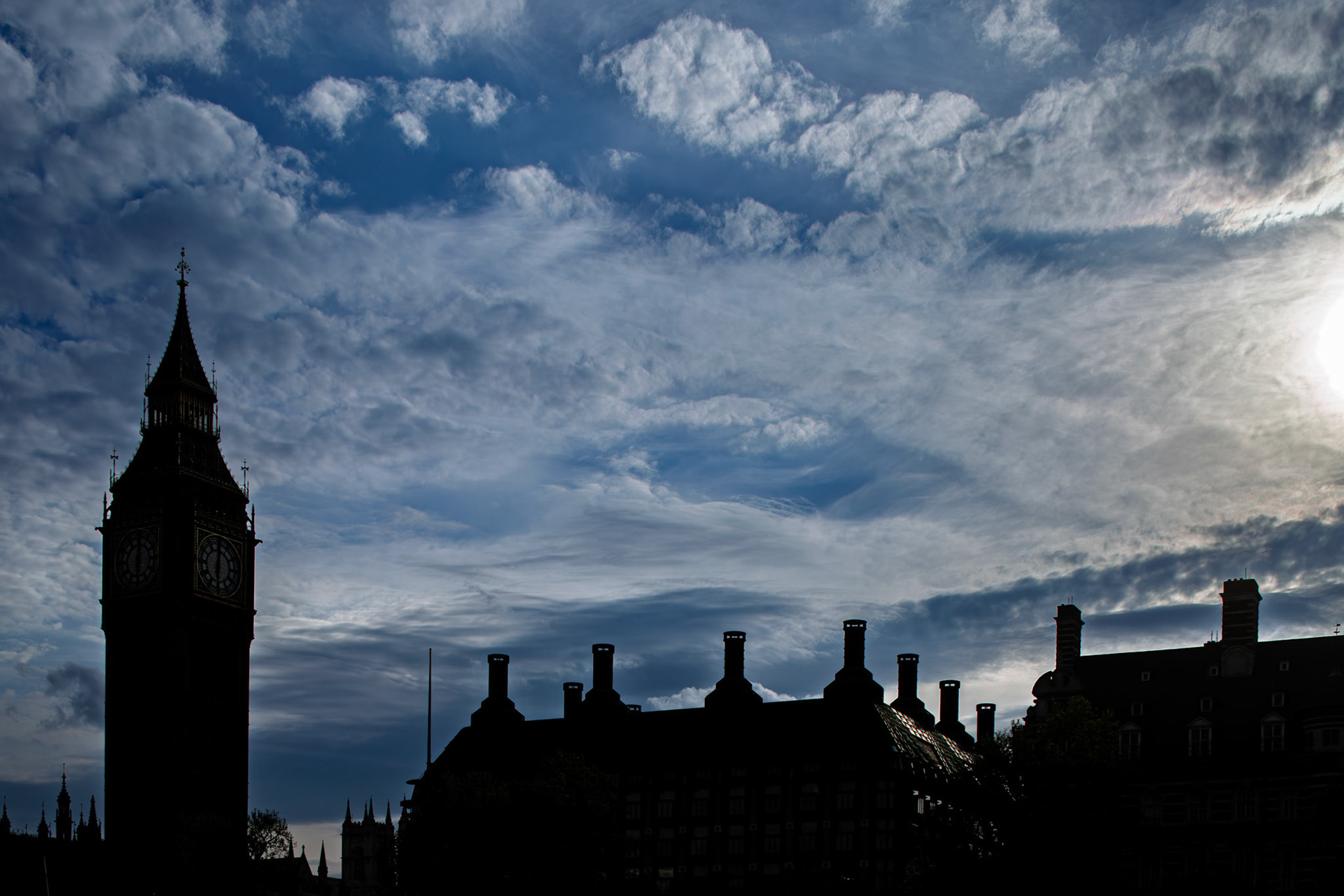 Big Ben stands tall against a backdrop of clouds in the evening sky. The clock tower is part of London's historic landscape as the sun sets.