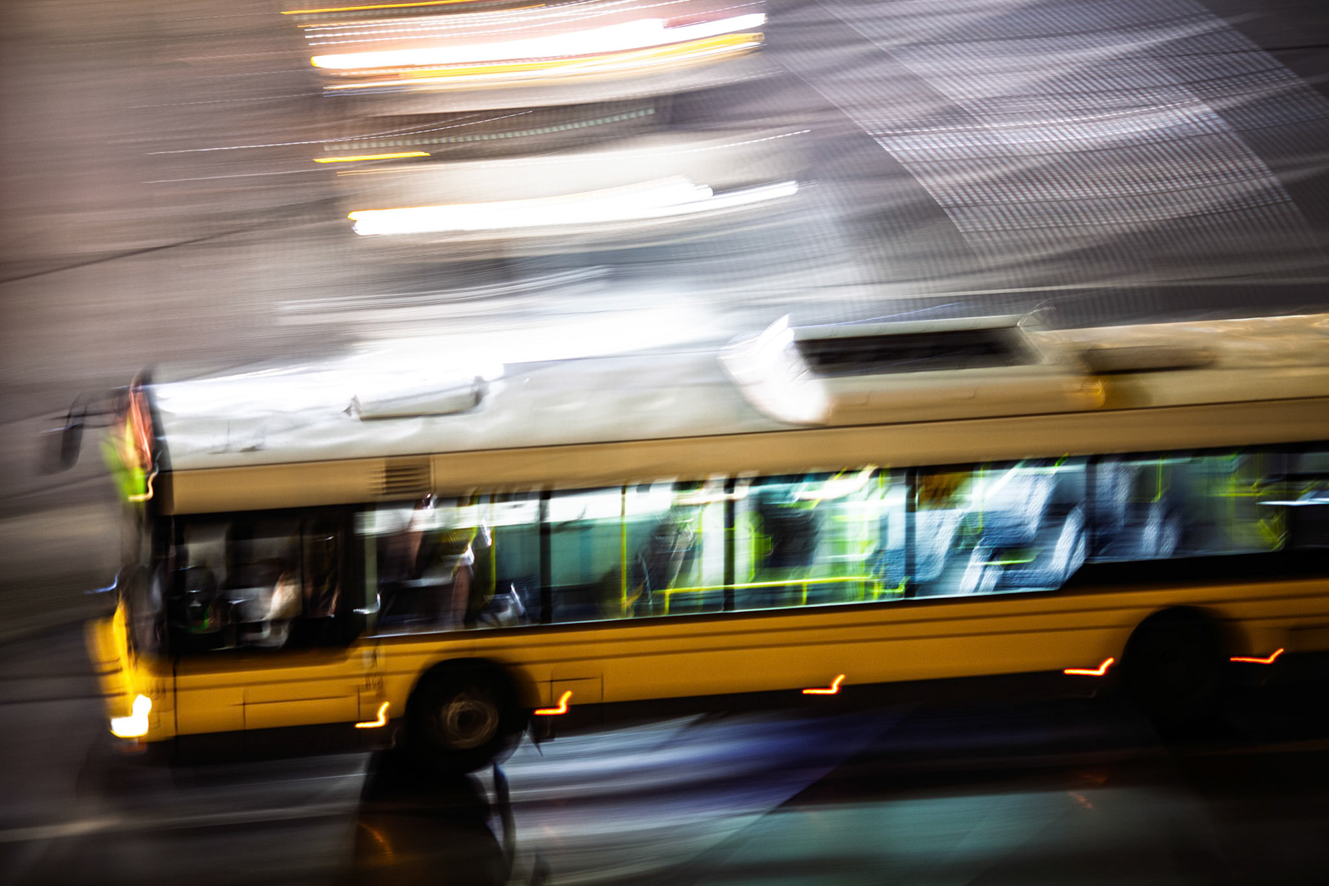A bus travels through the streets of Berlin at night, illuminated by city lights and creating a lively nighttime atmosphere.