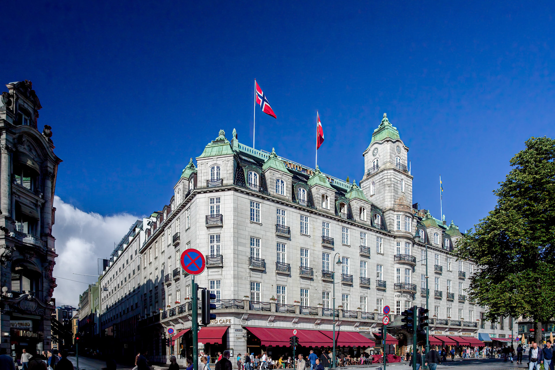 Oslo, Norway, Aug 10 2017, Grand Hotel stands prominently on Karl Johans street, with flags waving and patrons enjoying the outdoor cafe on a sunny day.