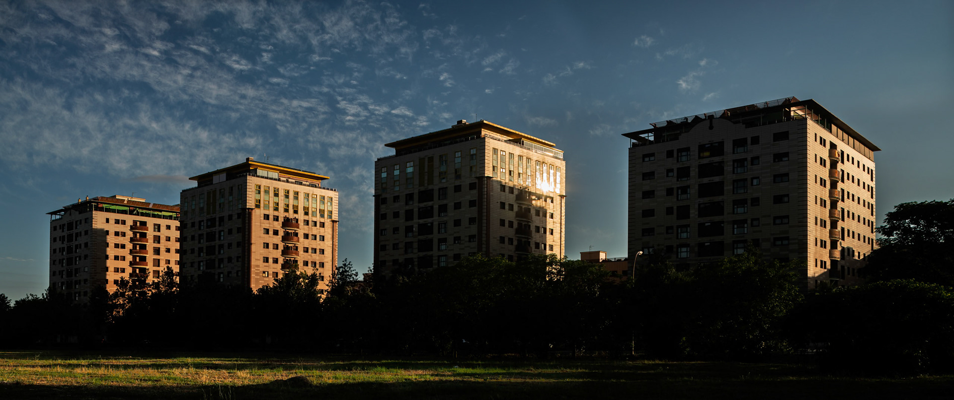 Four modern residential buildings stand against a clear sky in Los Bermejales, Seville, highlighting contemporary architecture in the area.