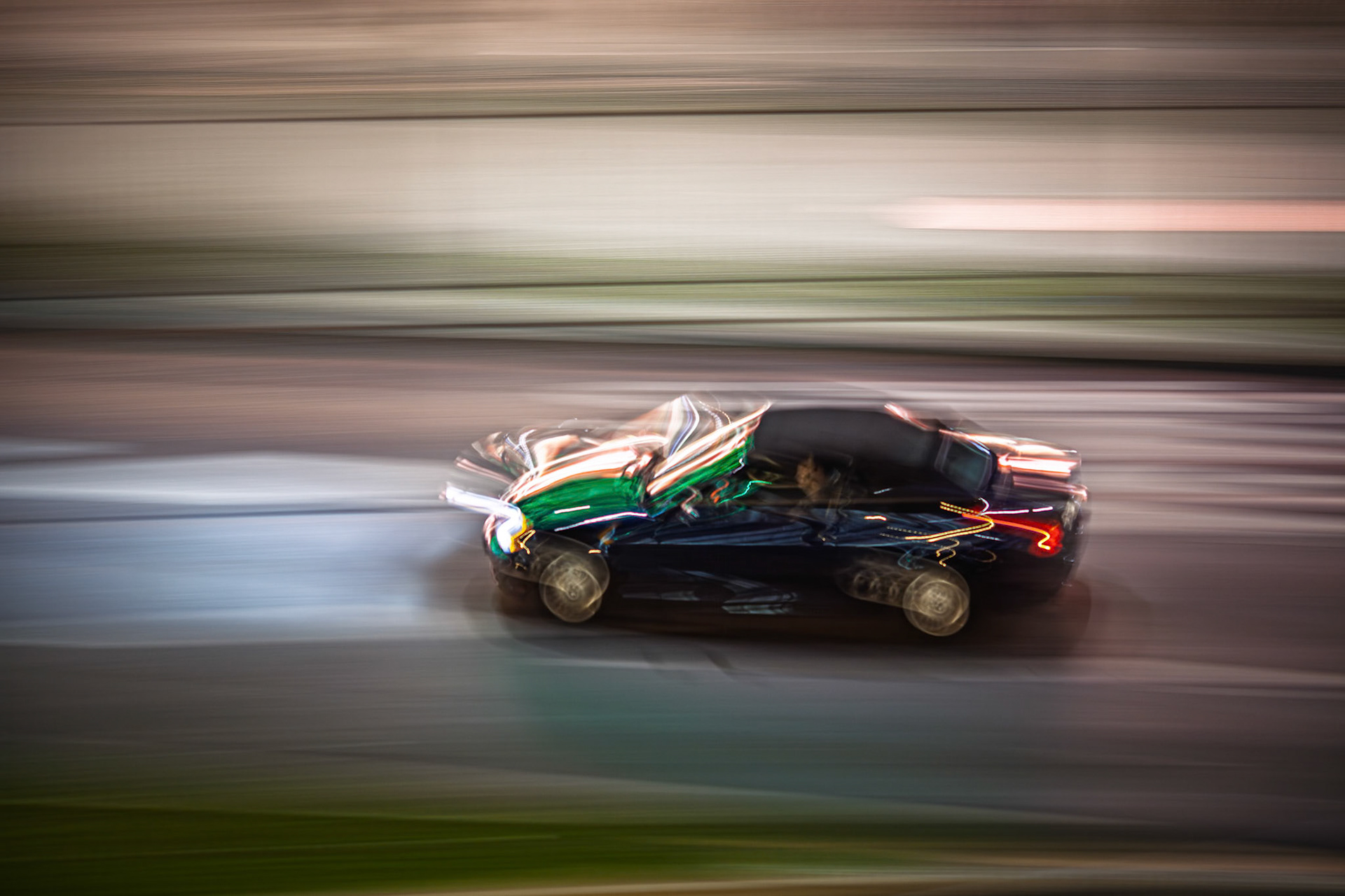 A sleek car moves swiftly through the streets of Berlin at night, captured in a dynamic panning shot that showcases the vibrant urban lights.