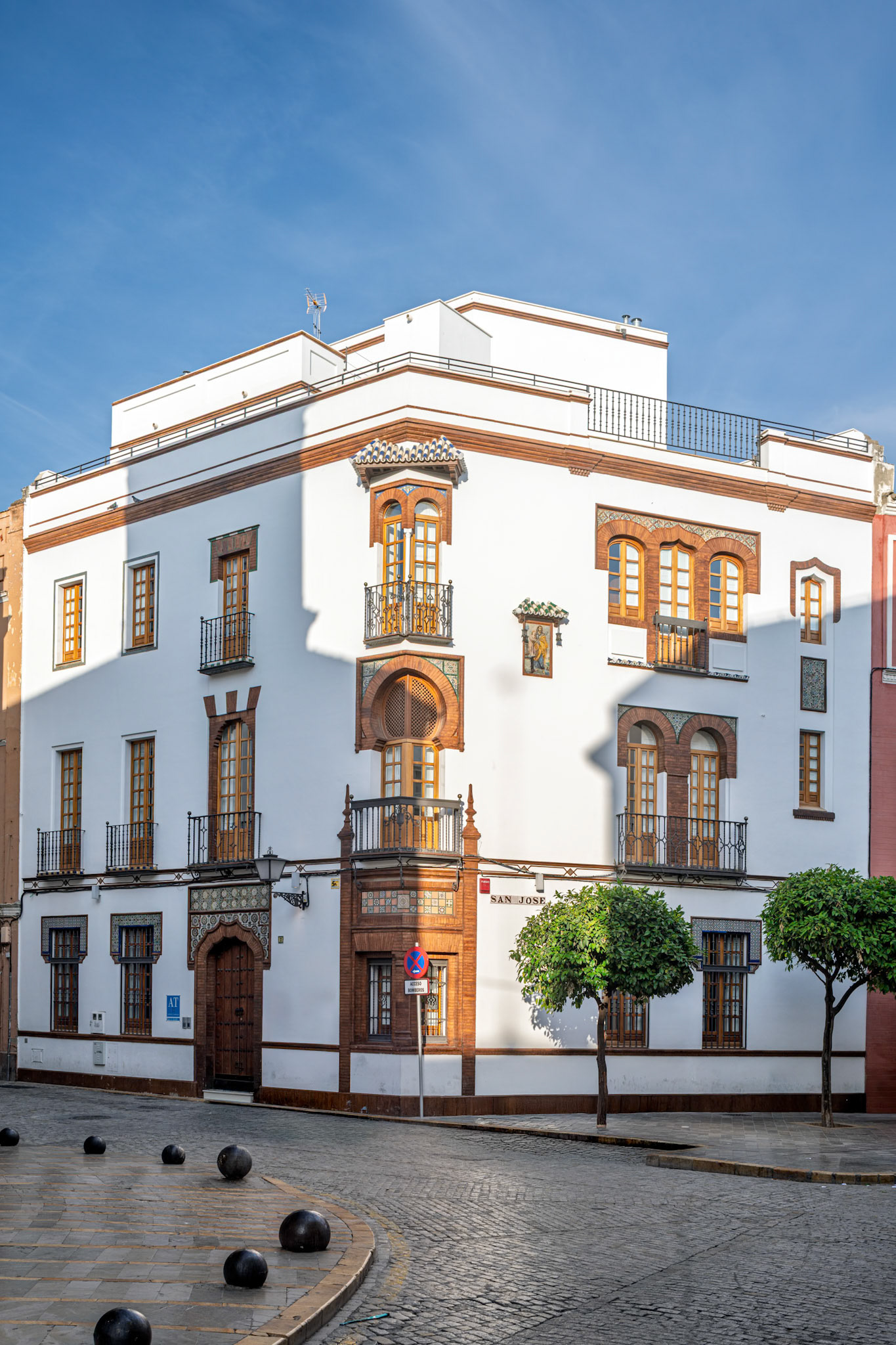 Captures a renovated early twentieth century palace on San Jose Street, Seville, now functioning as a hotel accommodation in sunny conditions.