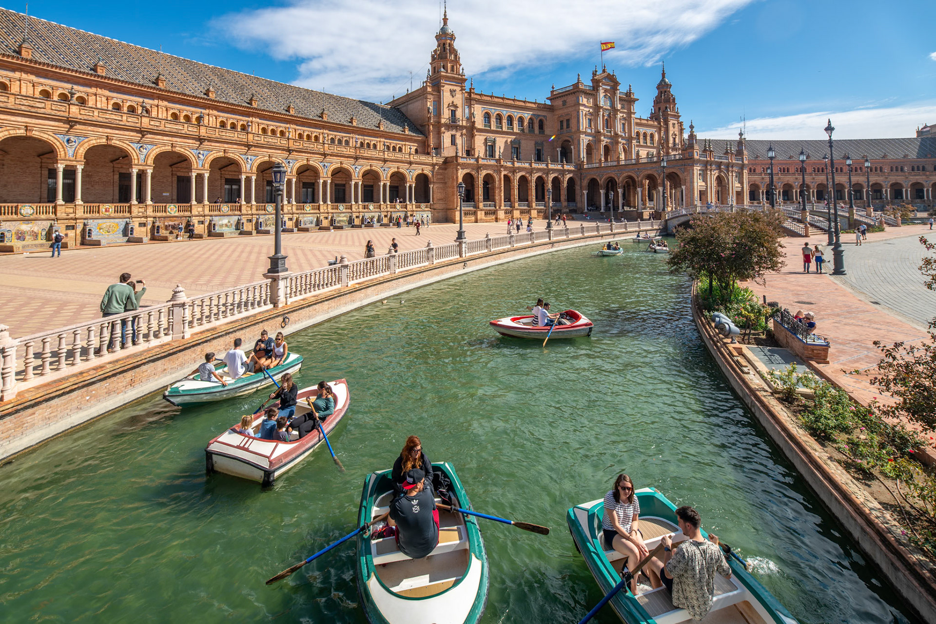 Visitors rowing in boats on the canal at the Plaza de España in Seville.