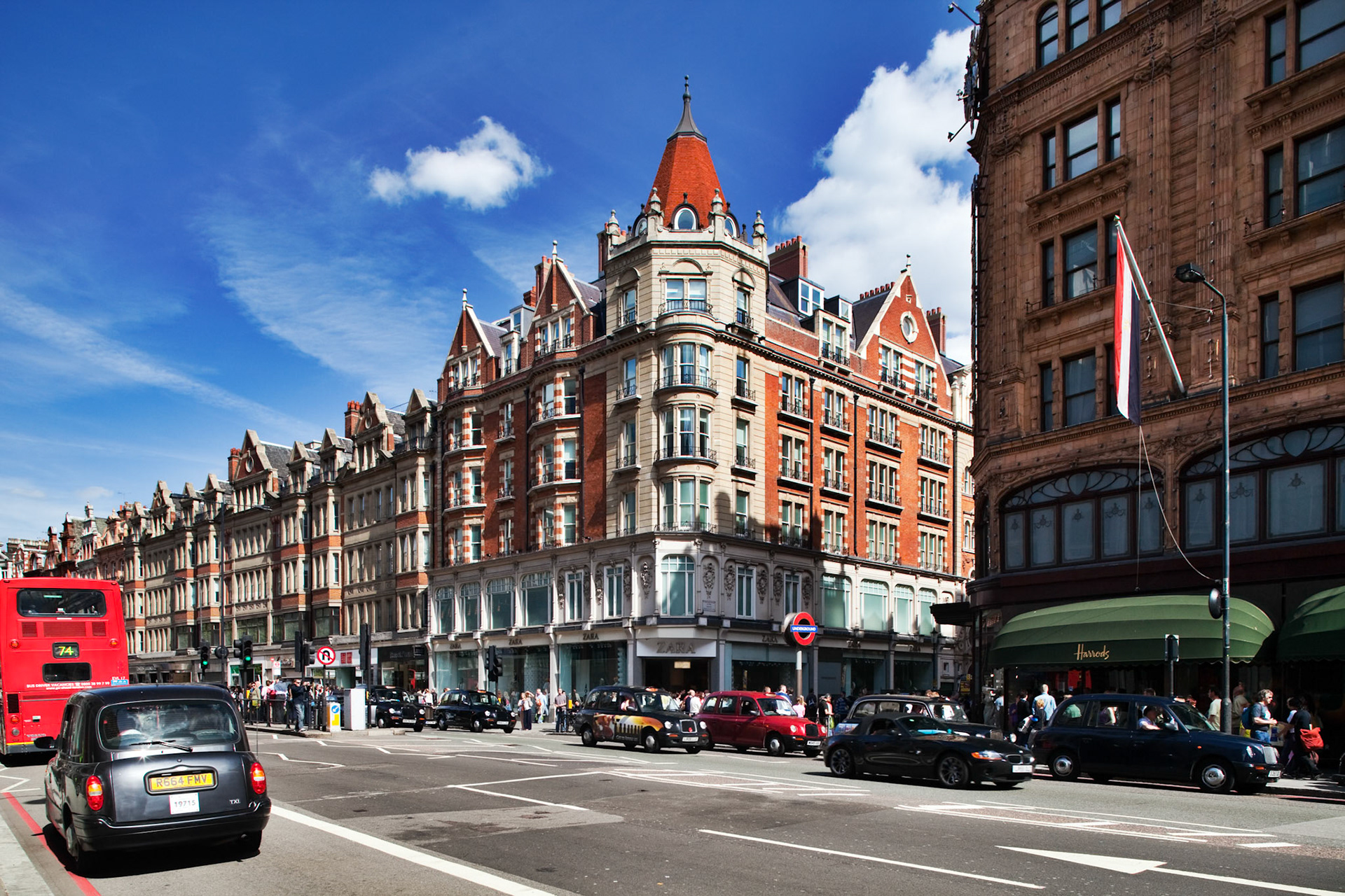 London, UK, May 2 2009, Busy street in London showcases the stunning architecture of 79 Brompton Road, filled with classic cars and pedestrians enjoying the day.