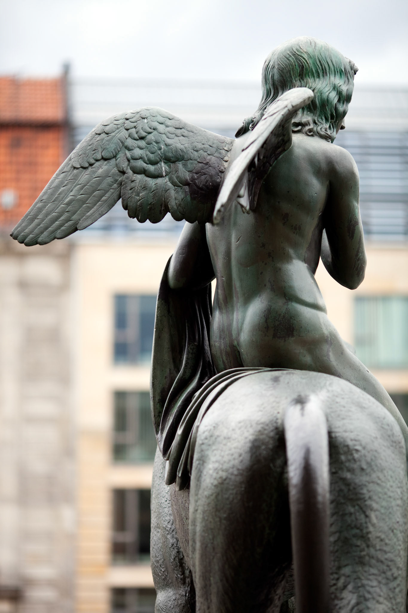A striking bronze statue depicting a winged figure atop a horse stands at Gendarmenmarkt square in Berlin, showcasing artistic elegance.