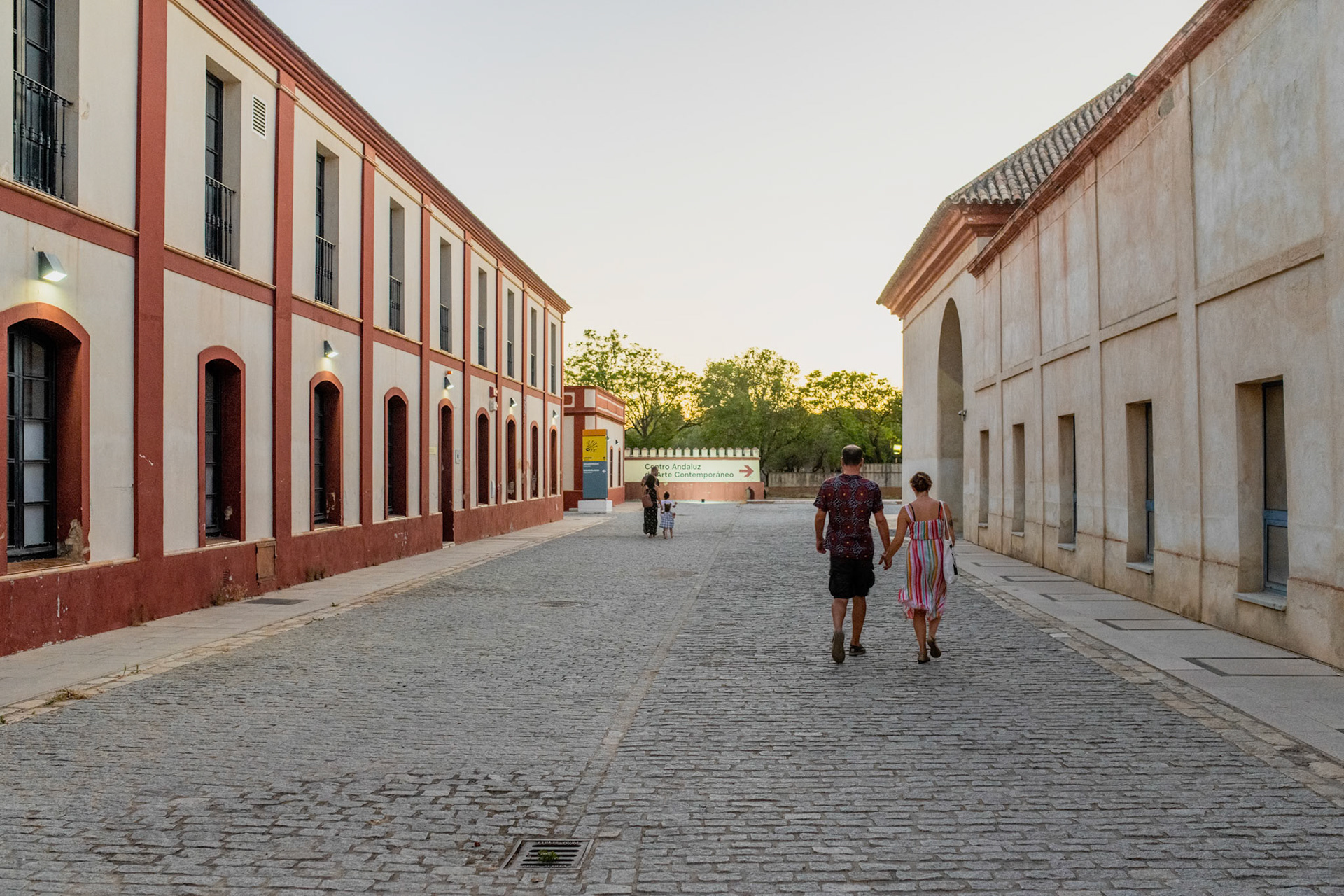 Seville, Spain, July 19 2022, Serene view of a couple strolling by Centro Andaluz de Arte Contemporaneo at sunset.