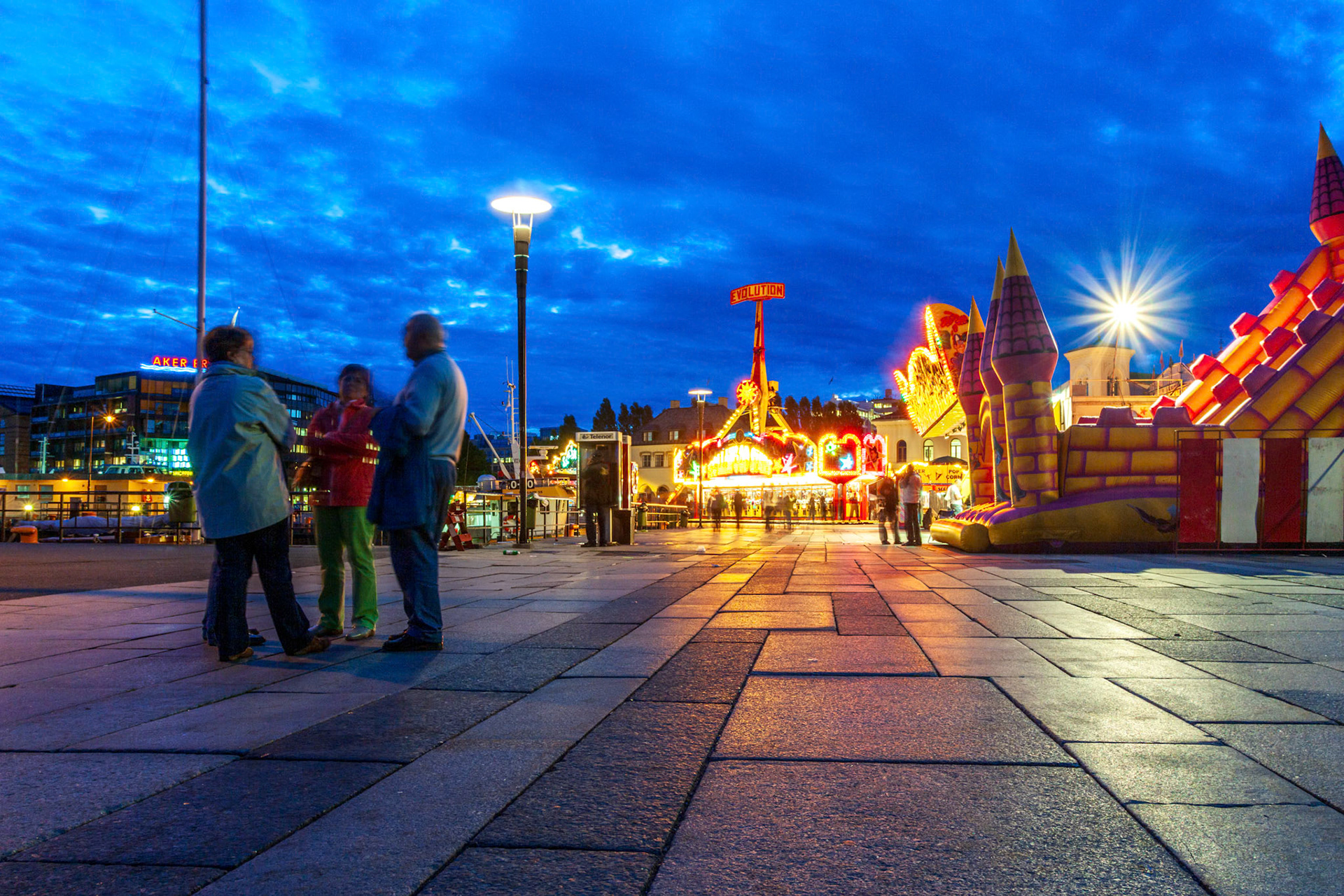 Oslo, Norway, Aug 10 2017, Colorful lights illuminate the fun fair at Aker Brygge as people enjoy activities under a twilight sky in downtown Oslo.