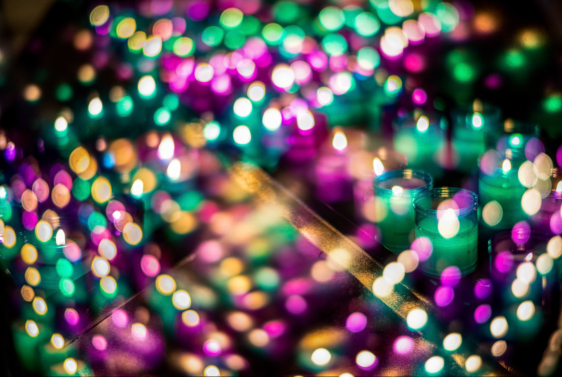 Votive candles in purple (for Passion of Christ) and green (for Esperanza Macarena) at the Basilica of Macarena atrium, Seville. Double exhibition bokeh.
