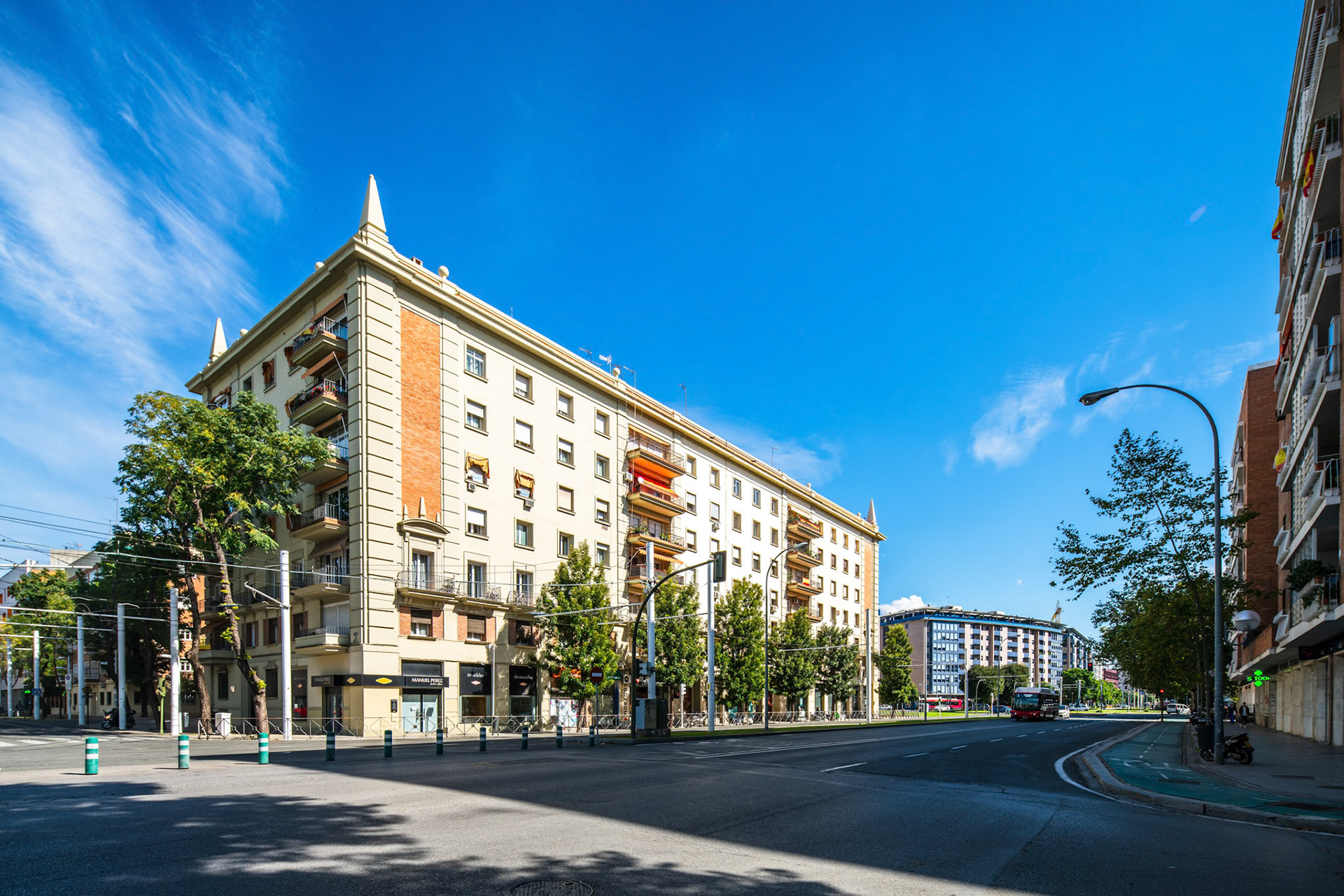 Residential building basked in sunlight at Prado de San Sebastian, with pedestrians and greenery.
