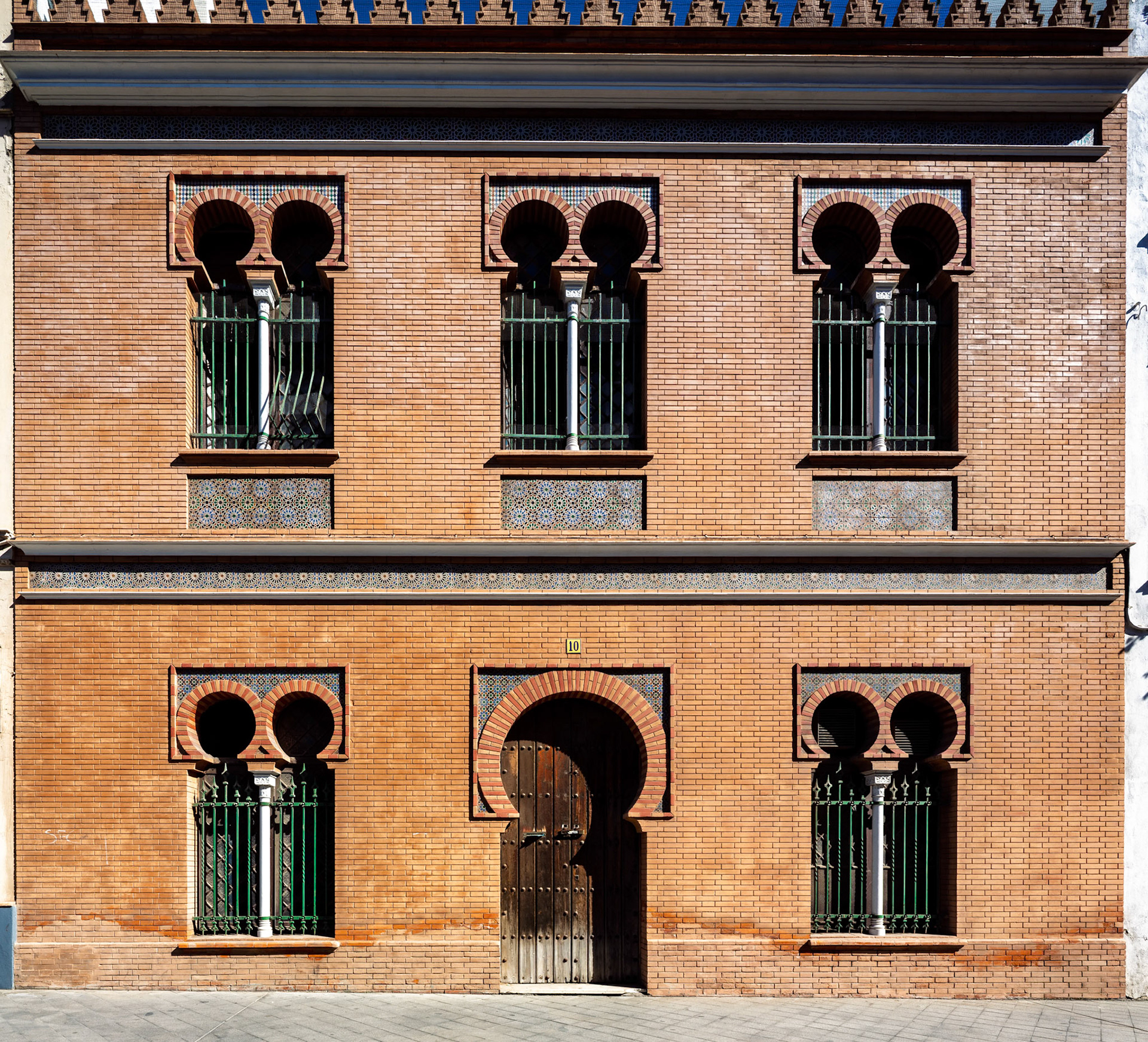 Intricate brickwork showcases the neomudéjar style of Antonio Arévalo's 1910 design in Seville, exemplifying cultural heritage.