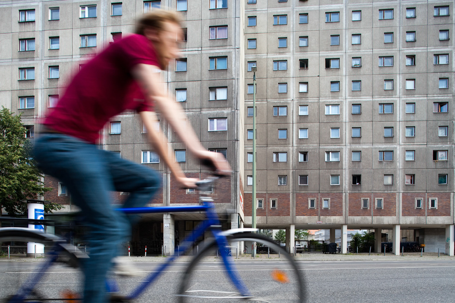 A cyclist pedals by a characteristic Socialist-era building in former East Berlin, showcasing urban life and historical architecture.
