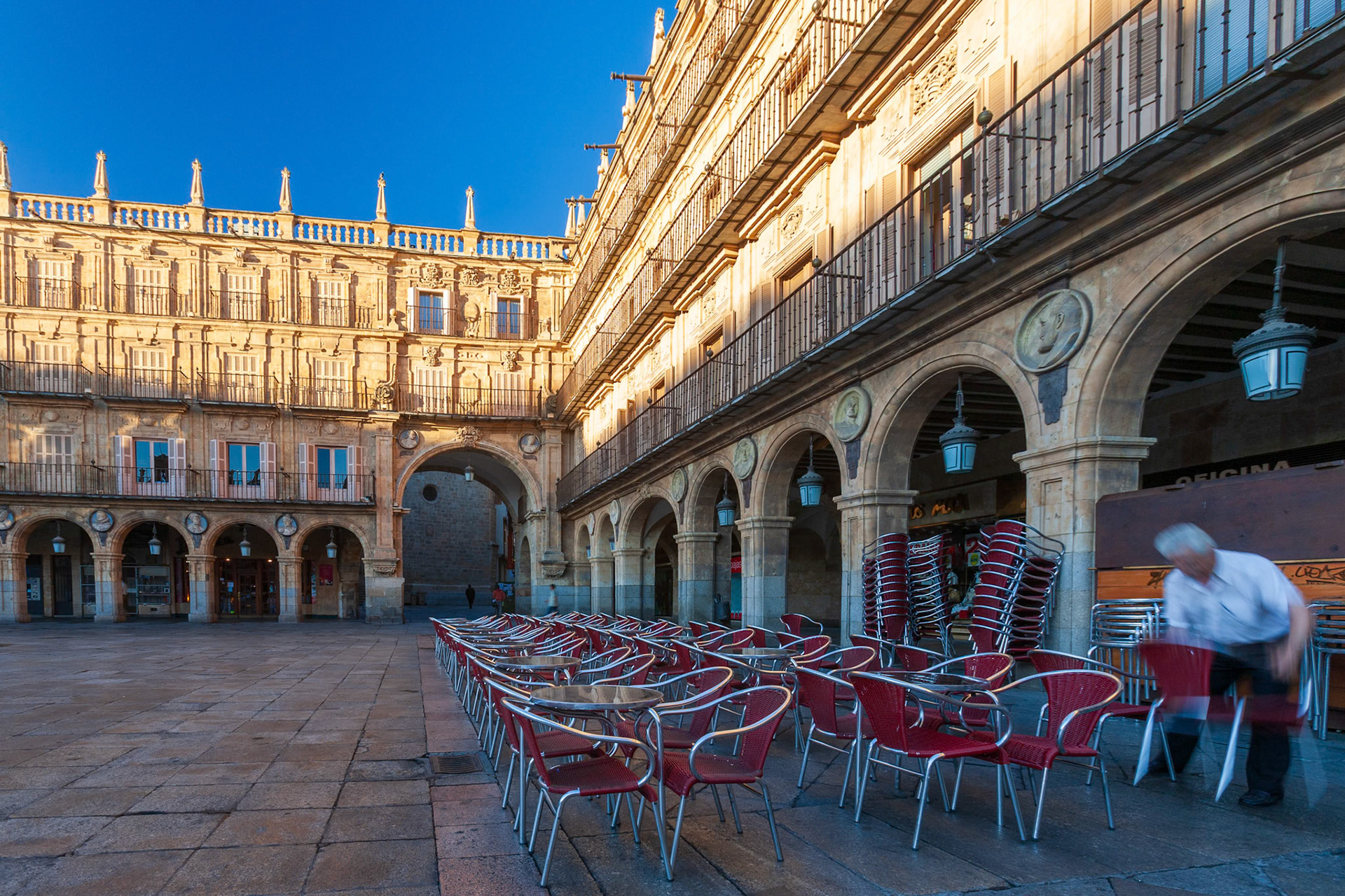 Chairs arranged at dawn in Salamanca's famous Plaza Mayor, showcasing architectural elegance.