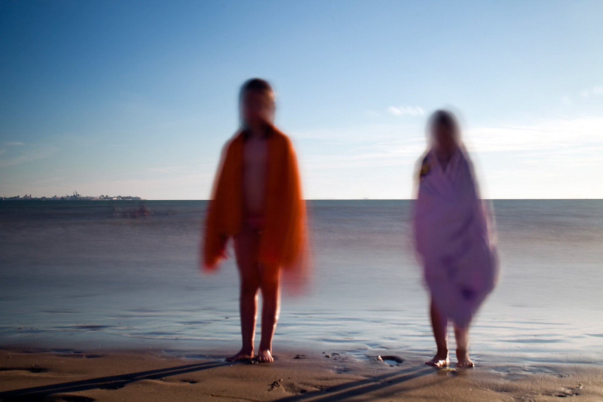 Little girls standing on the beach, El Puerto de Santa Maria, Spain. Daylight long exposure shot by the use of neutral density filters.